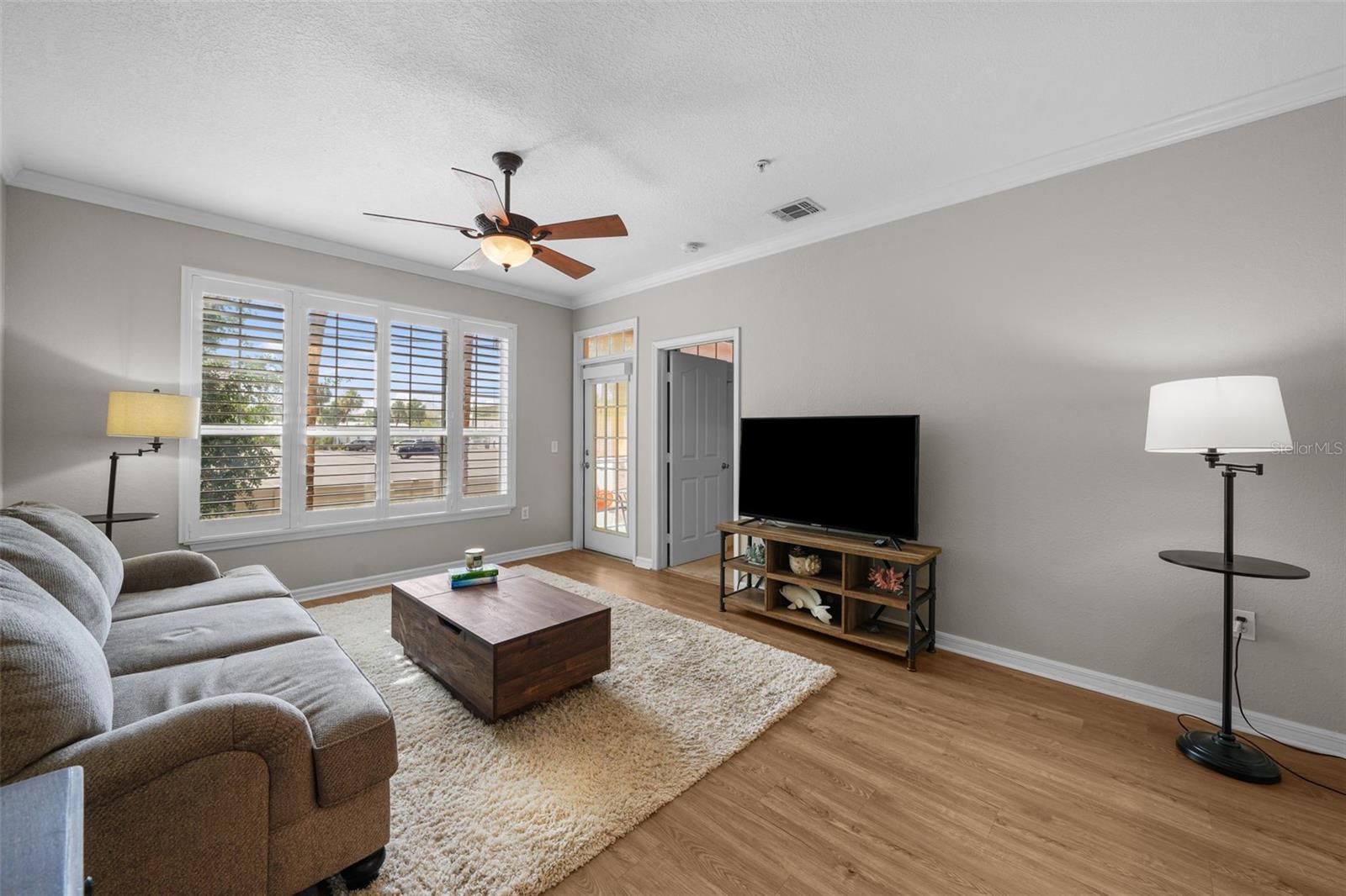 Spacious Living Room features LVP flooring, plantation shutters, & door to Patio.
