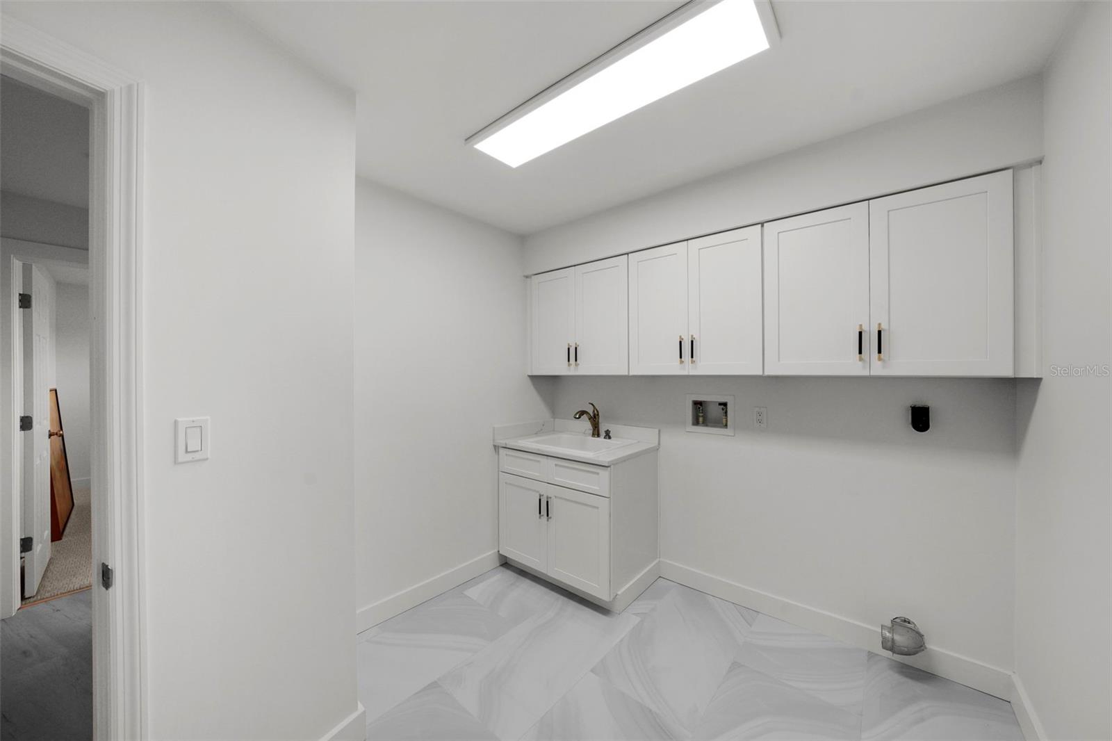 Redesigned laundry room includes laundry sink, and plenty of cabinets with additional space for your personal cleaning needs
