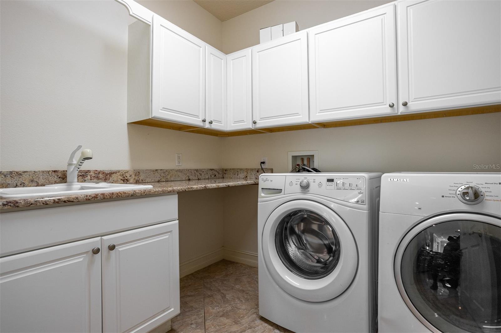 Spacious indoor laundry room with lots of additional storage and large farmhouse sink