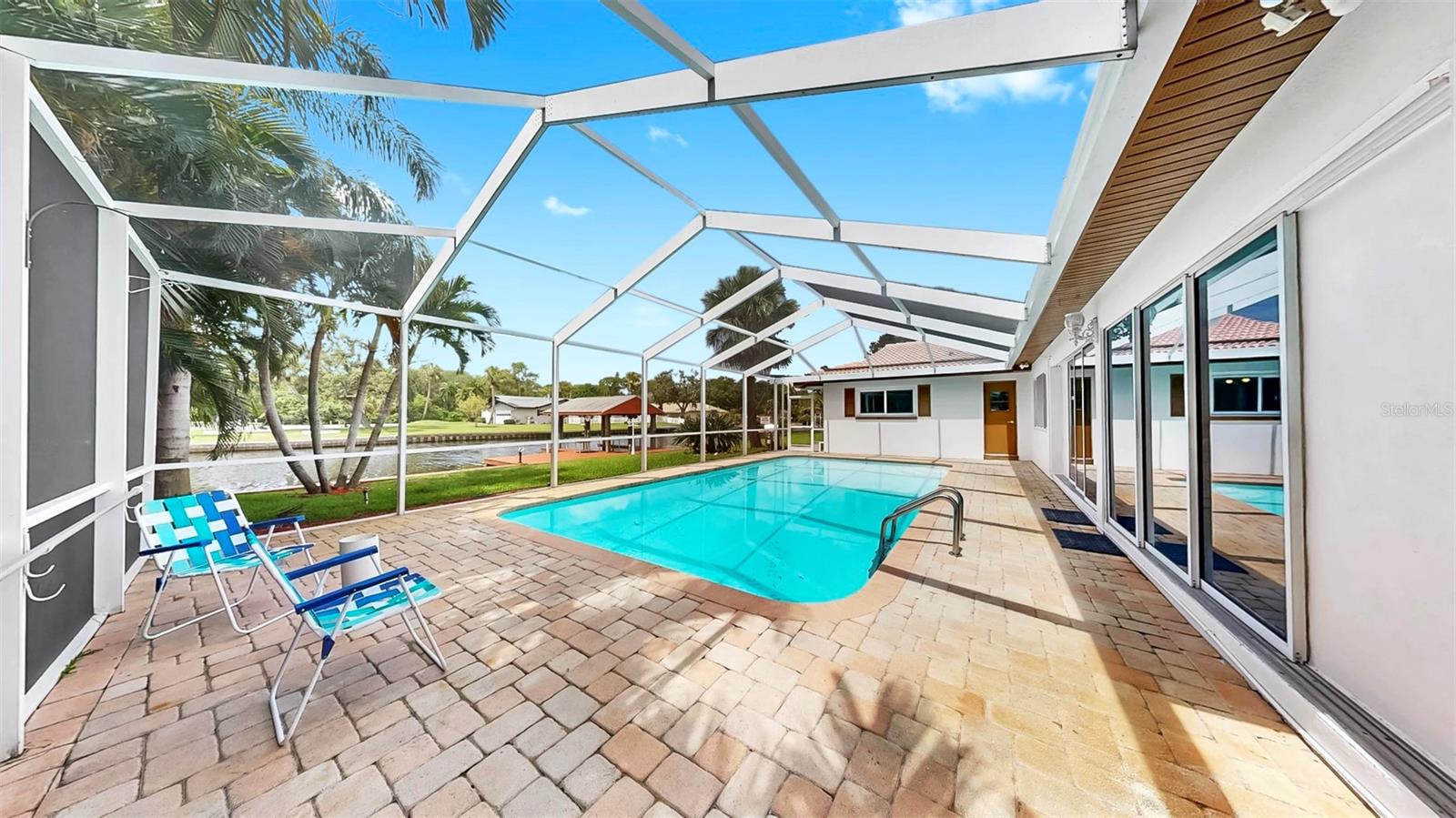 Awwwmazing pavered, screened-in pool area with waterfront views!