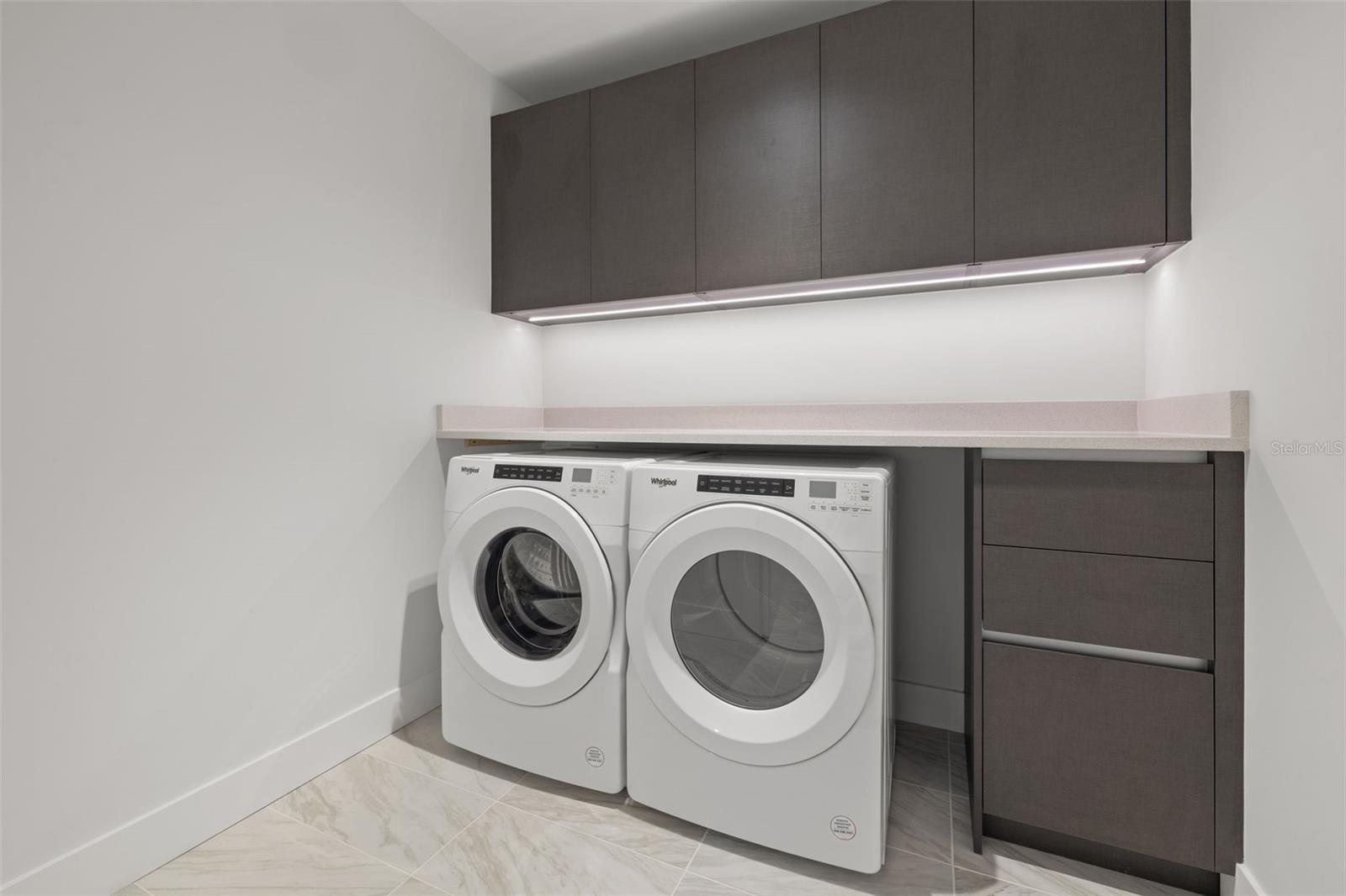 Full size laundry room with Whirlpool washer and dryer, upper cabinetry and under cabinet lighting and room to add a utility sink.