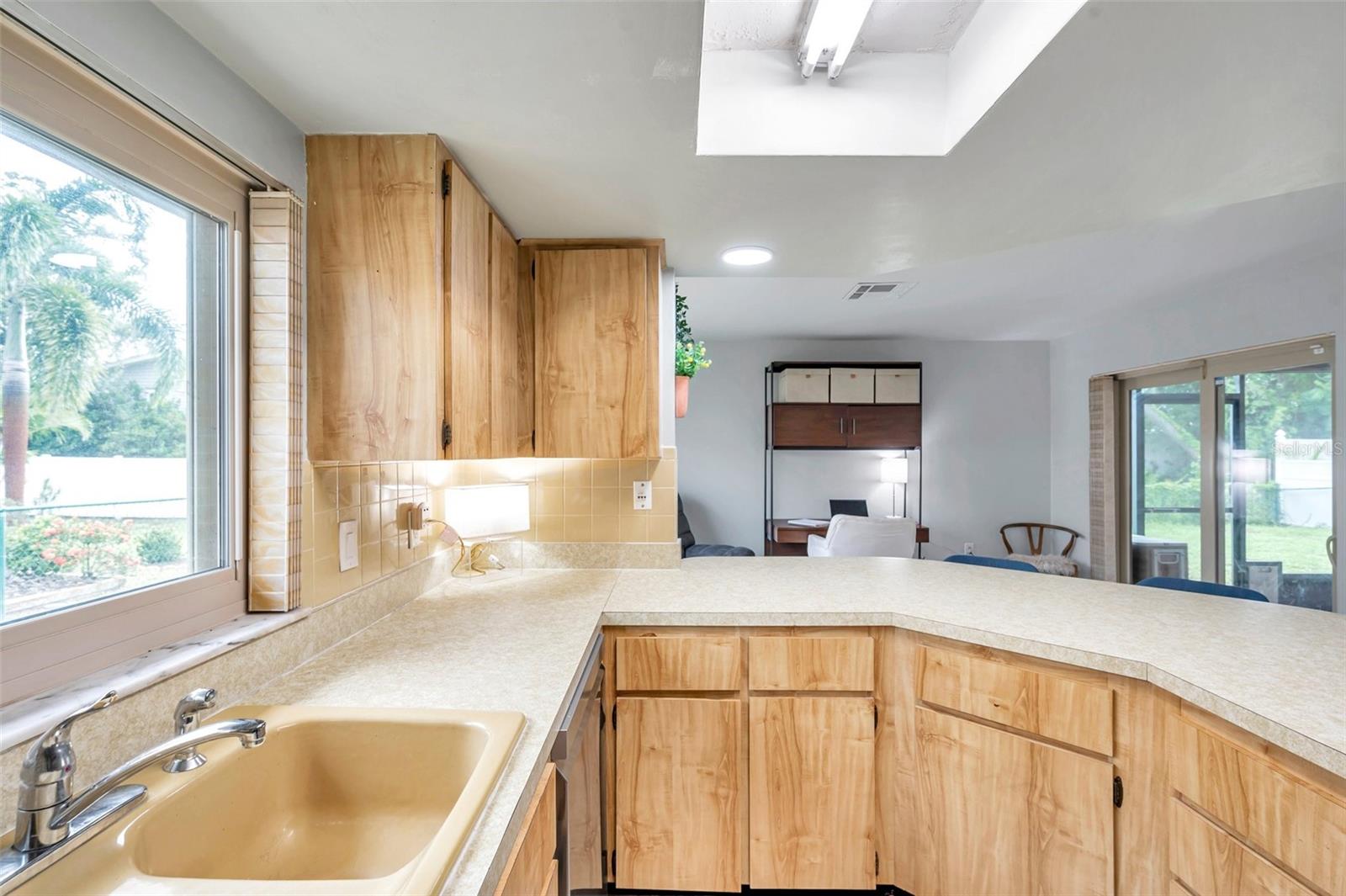 Well lit kitchen, big window and sliders leading to screened porch.