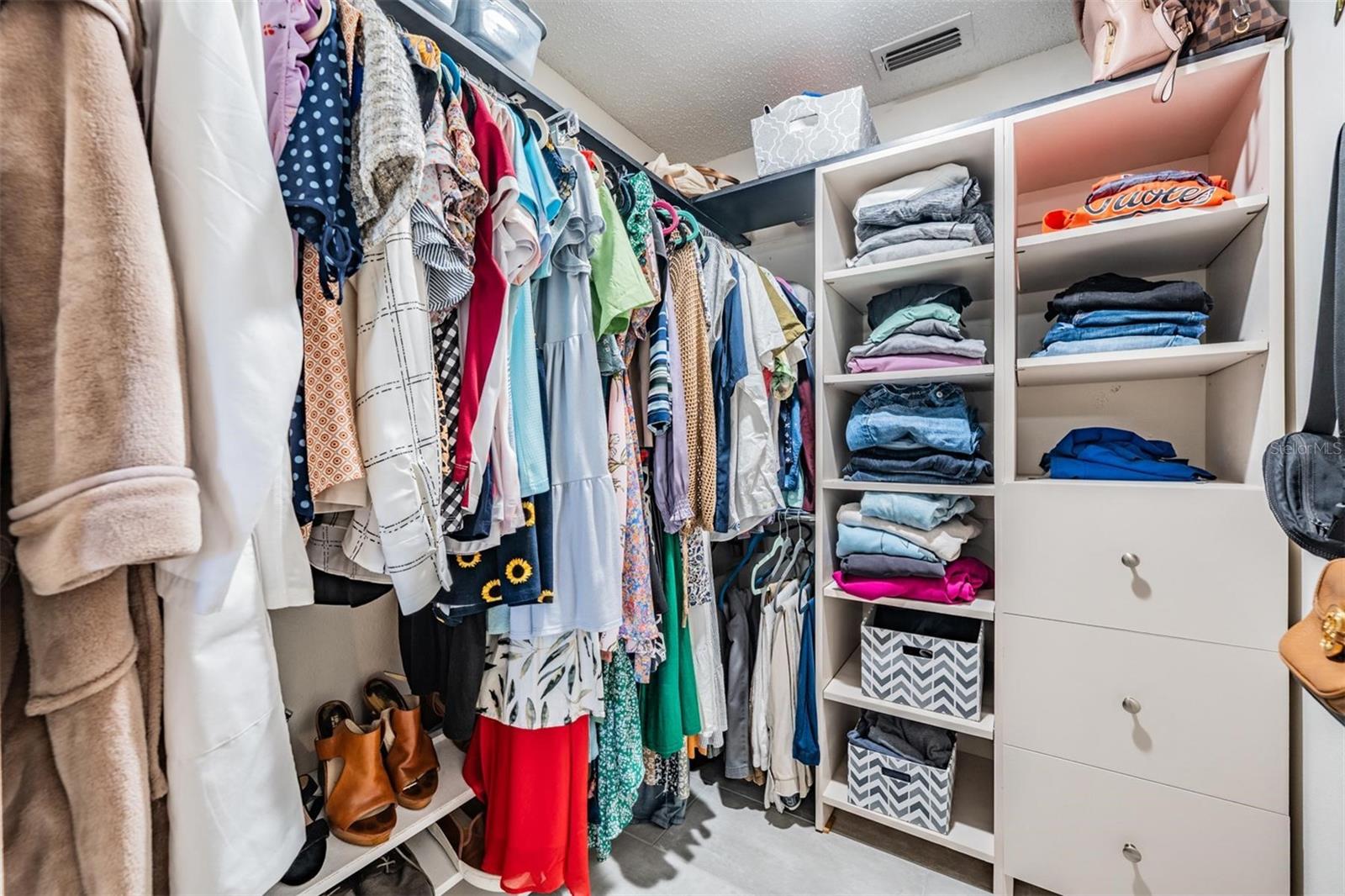 Primary bedroom walk-in closet with built-in storage