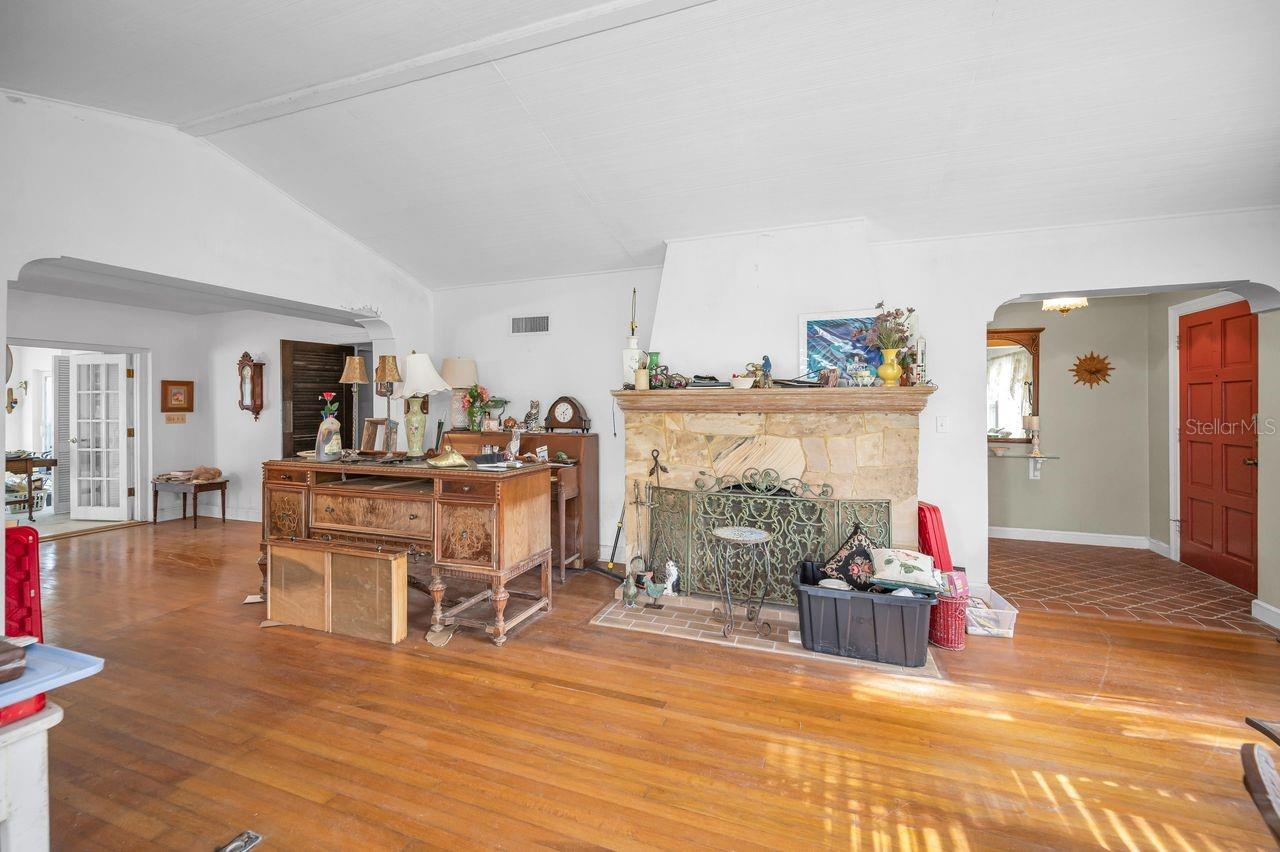 Just look at all the details in this one photo! Stone fireplace, detailed archway, hardwood floors, beautiful bricks in entry, French doors into dining room, and more!