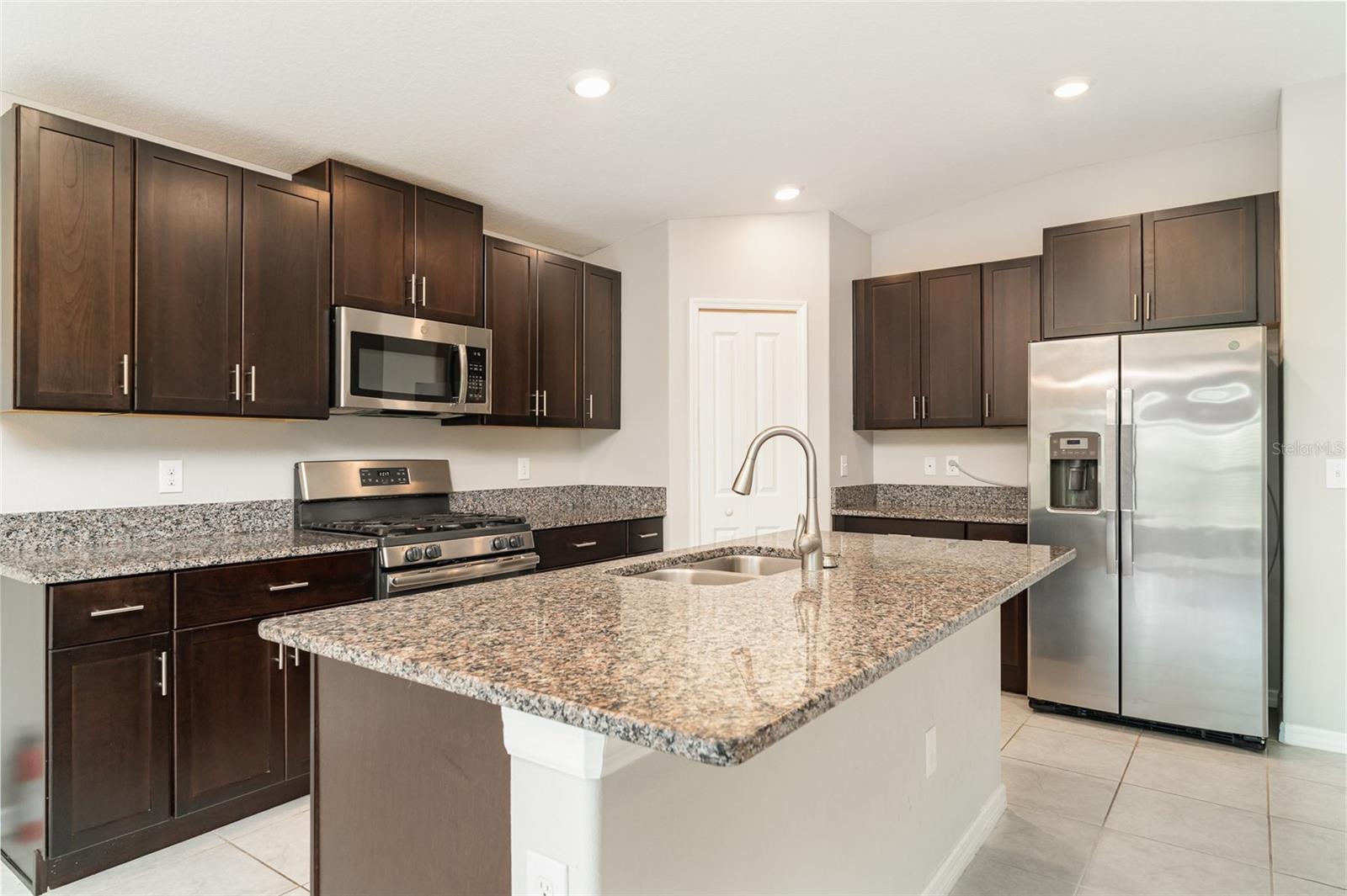 A CHEF’S KITCHEN with GRANITECOUNTERTOPS, STAINLESS STEEL APPLIANCES, a large KITCHEN ISLAND, and a WALK-IN PANTRY make it perfect for entertaining.