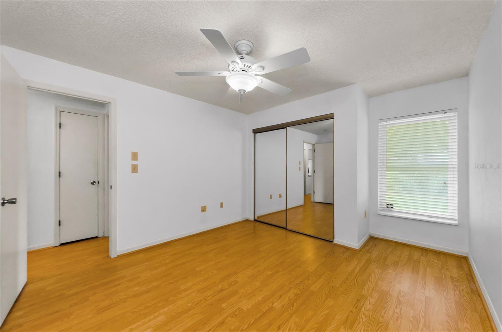 The primary bedroom has mirrored closet doors, closet system, and plenty of natural light.