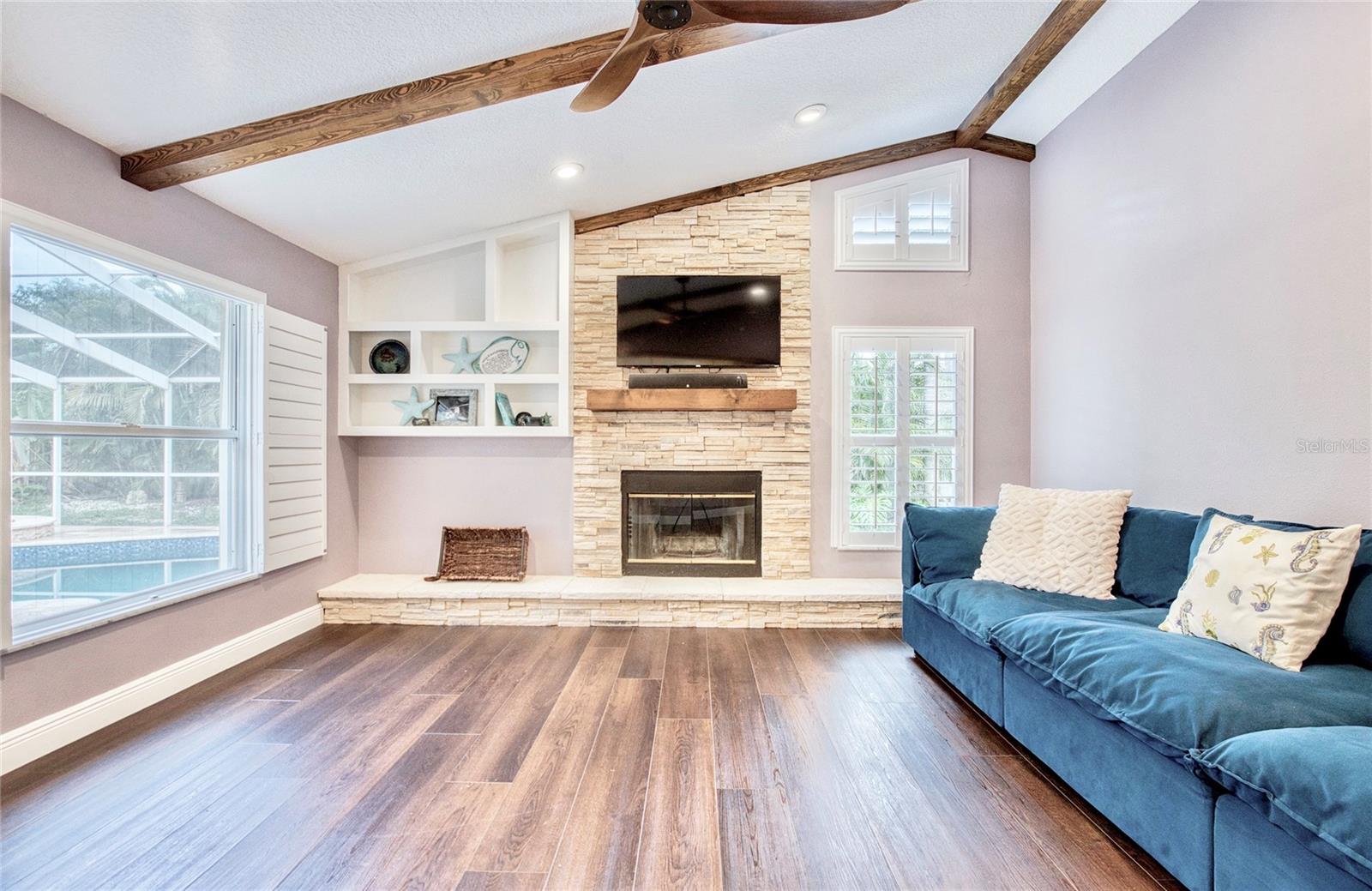 Enjoy stunning pool views from the spacious Great Room, featuring vaulted ceilings, a cozy fireplace, and elegant French doors that open directly to the poolside lanai—perfect for indoor-outdoor living.