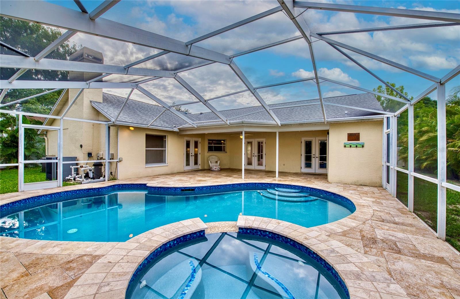 3 sets of French doors open to the lanai and screened pool area, creating a seamless connection between indoor and outdoor living spaces.