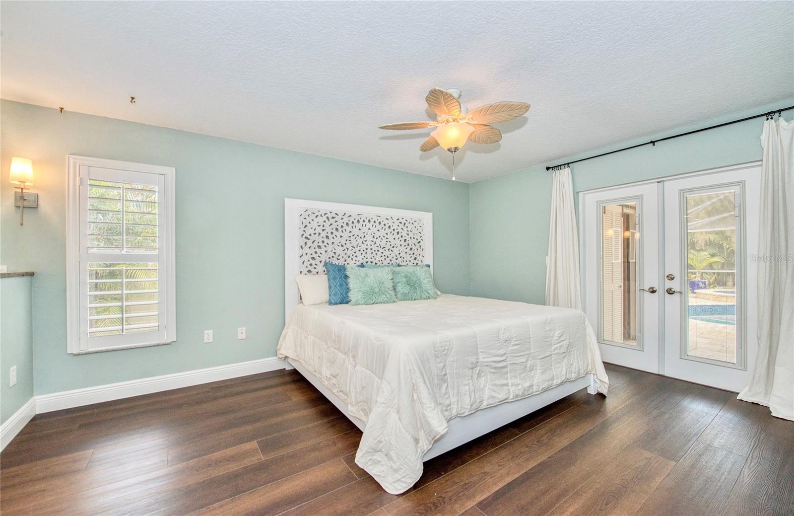 The en-suite primary bedroom showcases French doors leading directly to the pool lanai, providing private outdoor access and enhanced tranquility in a well-designed split-bedroom floorplan.