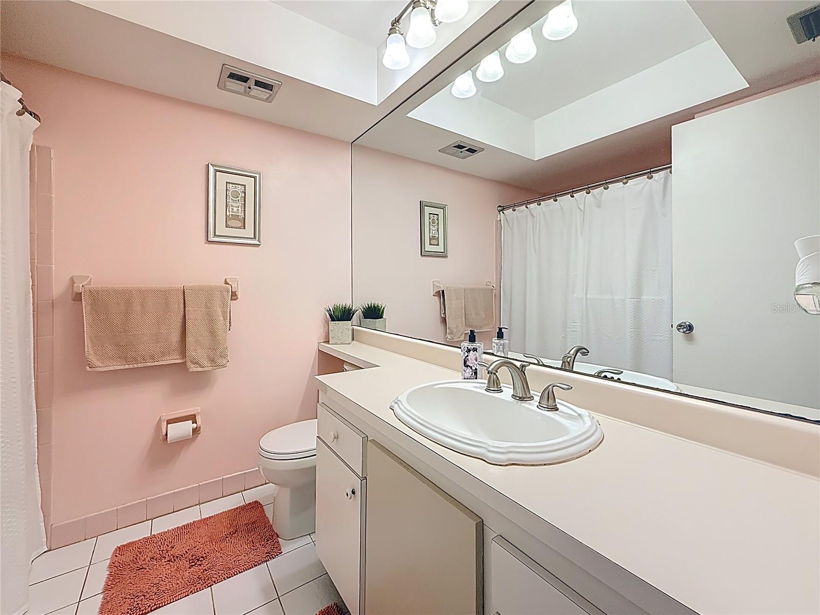 The second bathroom just steps from the bedroom features a tub with a shower.