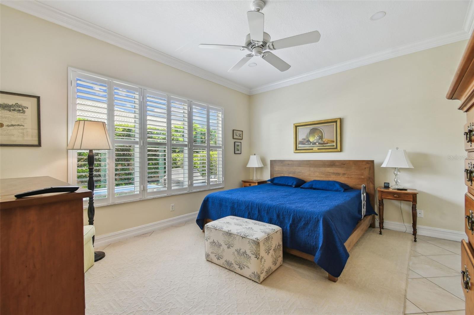 Large primary bedroom that easily fits a king bedframe and two side tables.  This room also is all tiled and is adorned with plantation shutters.