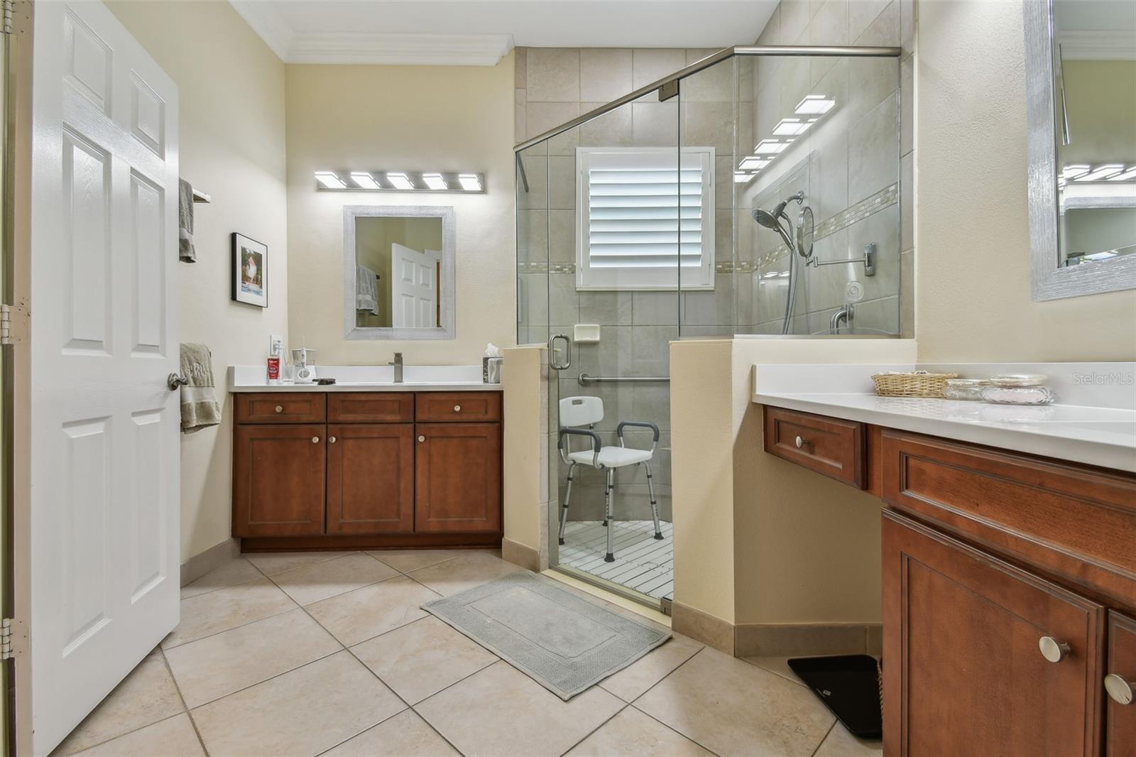 Primary bath - contains dual vanities, with NEW quartz tops, NEW plumbing fixtures, NEW custom lighting, and NEW glass shower enclosure.  The floor of the shower has also been modified for easy entrance.