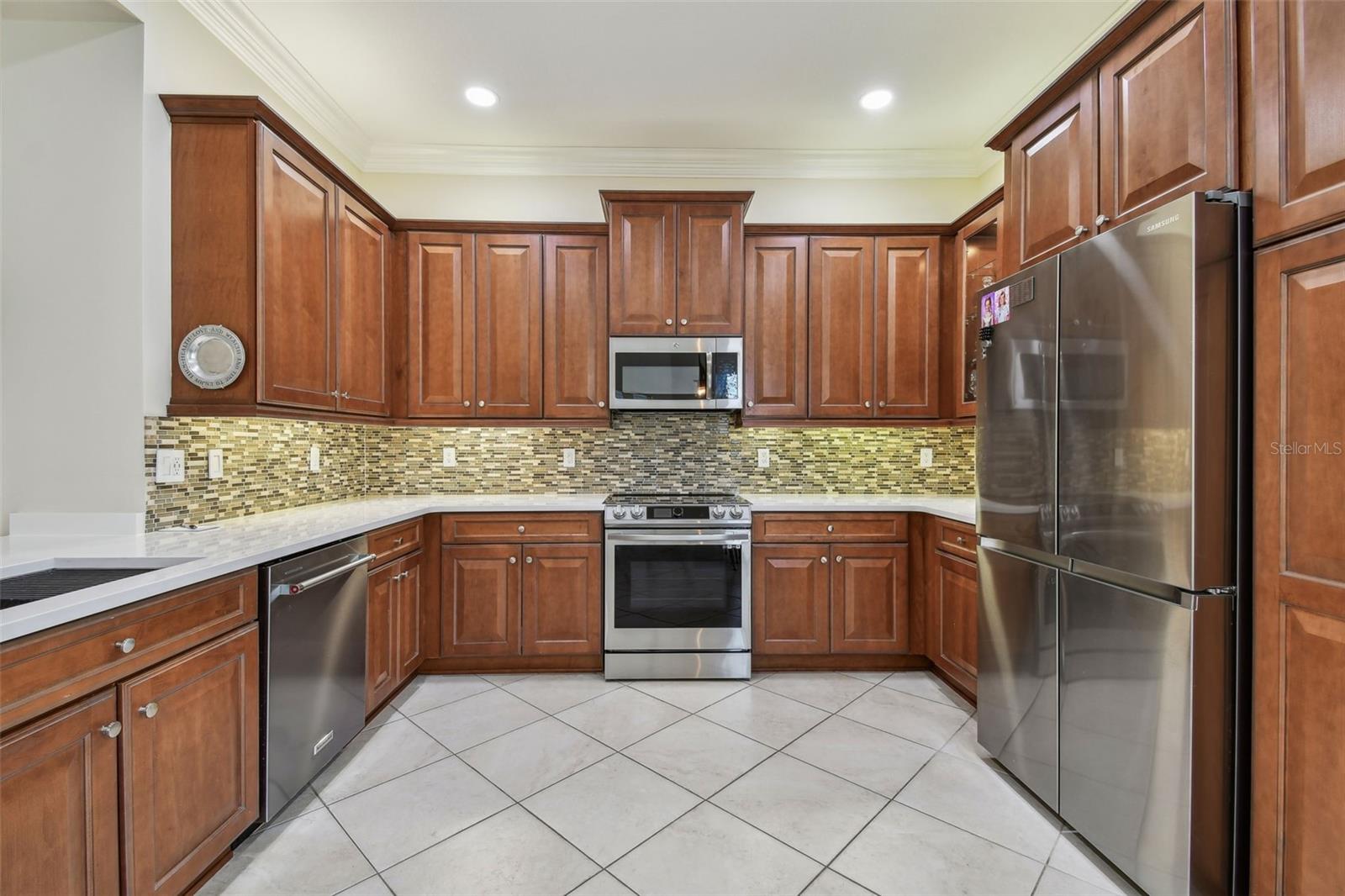Open kitchen contains NEW quartz counters, NEW sink, NEW custom faucet, tile backsplash, NEW appliances, pull out shelving in cabinets, over head and under cabinet lighting.