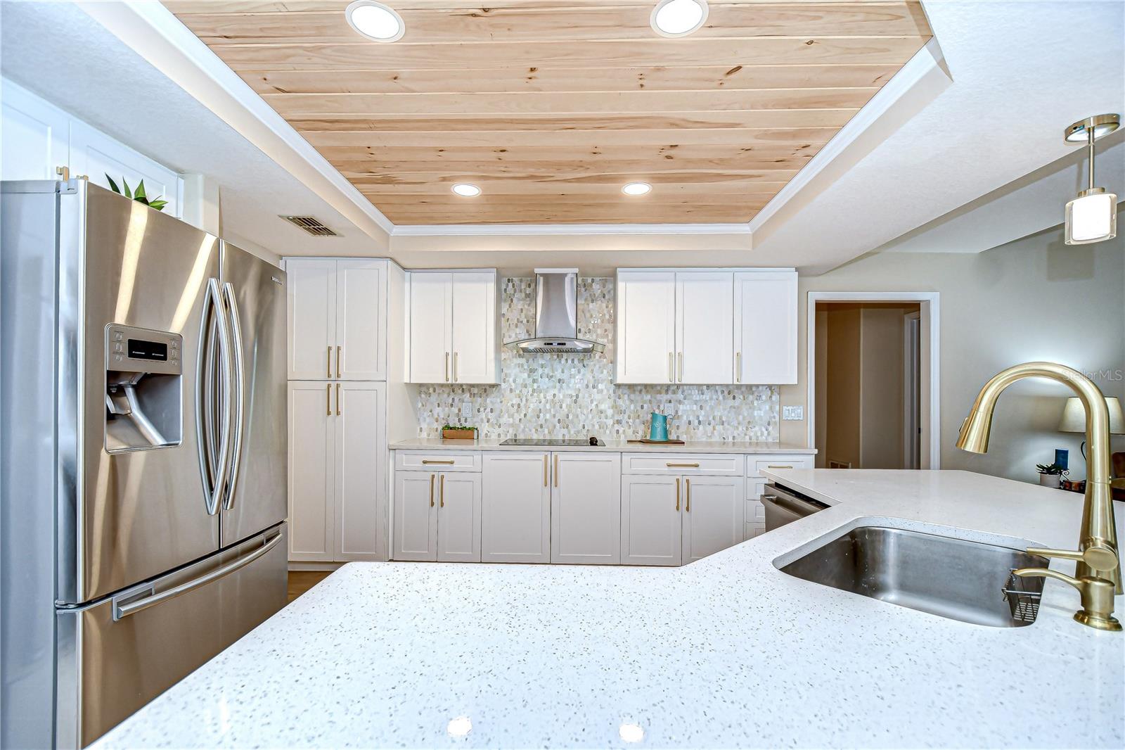Custom pantry closet, cooktop with hood, gorgeous tile backsplash.