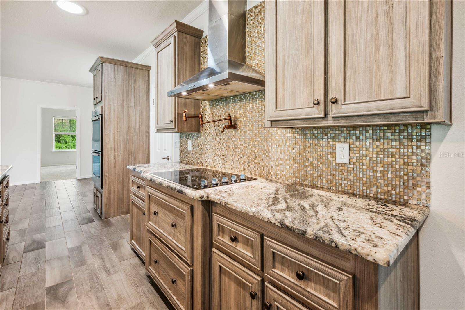 Featuring granite countertops, a custom-designed tile backsplash, a sleek stainless steel range hood, and many other high-end touches.