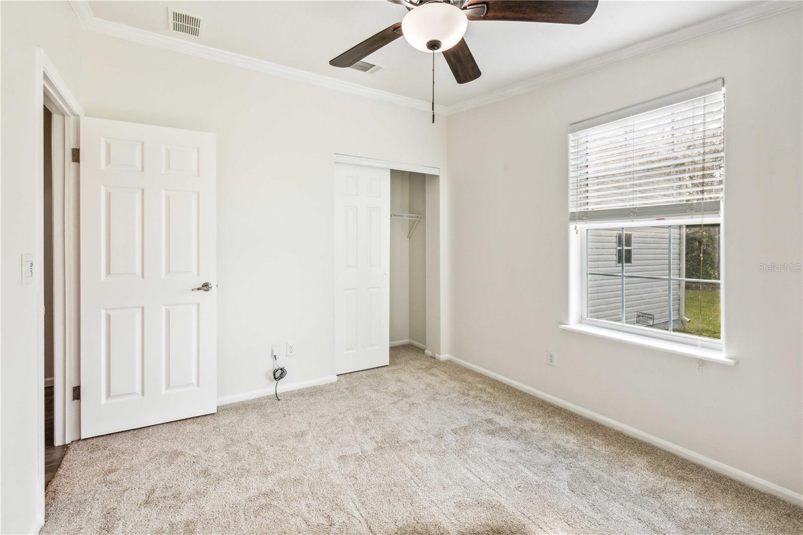 Bedroom four features a ceiling fan and brand-new carpeting.
