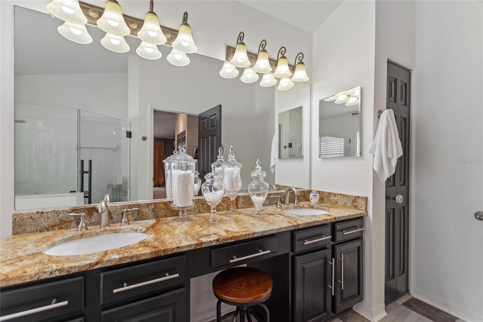 Primary bathroom has modern granite counters, lights and cabinetry.
