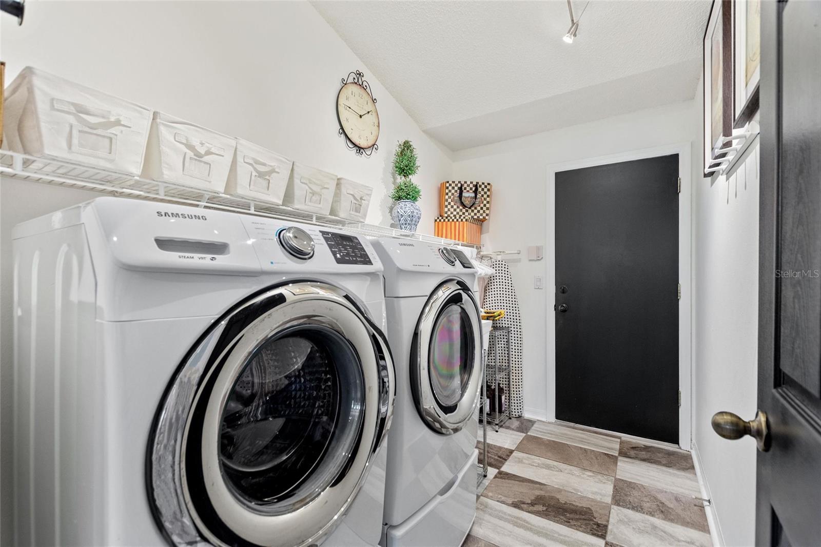 Laundry room is bright and airy with newer appliances and shelving.