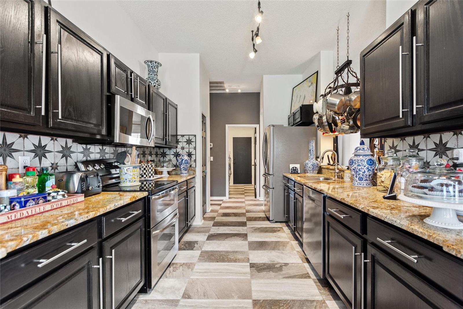 Look at all of the granite counter tops! Modern finishes really accentuate the kitchen area, especially the pot rack over the sink.