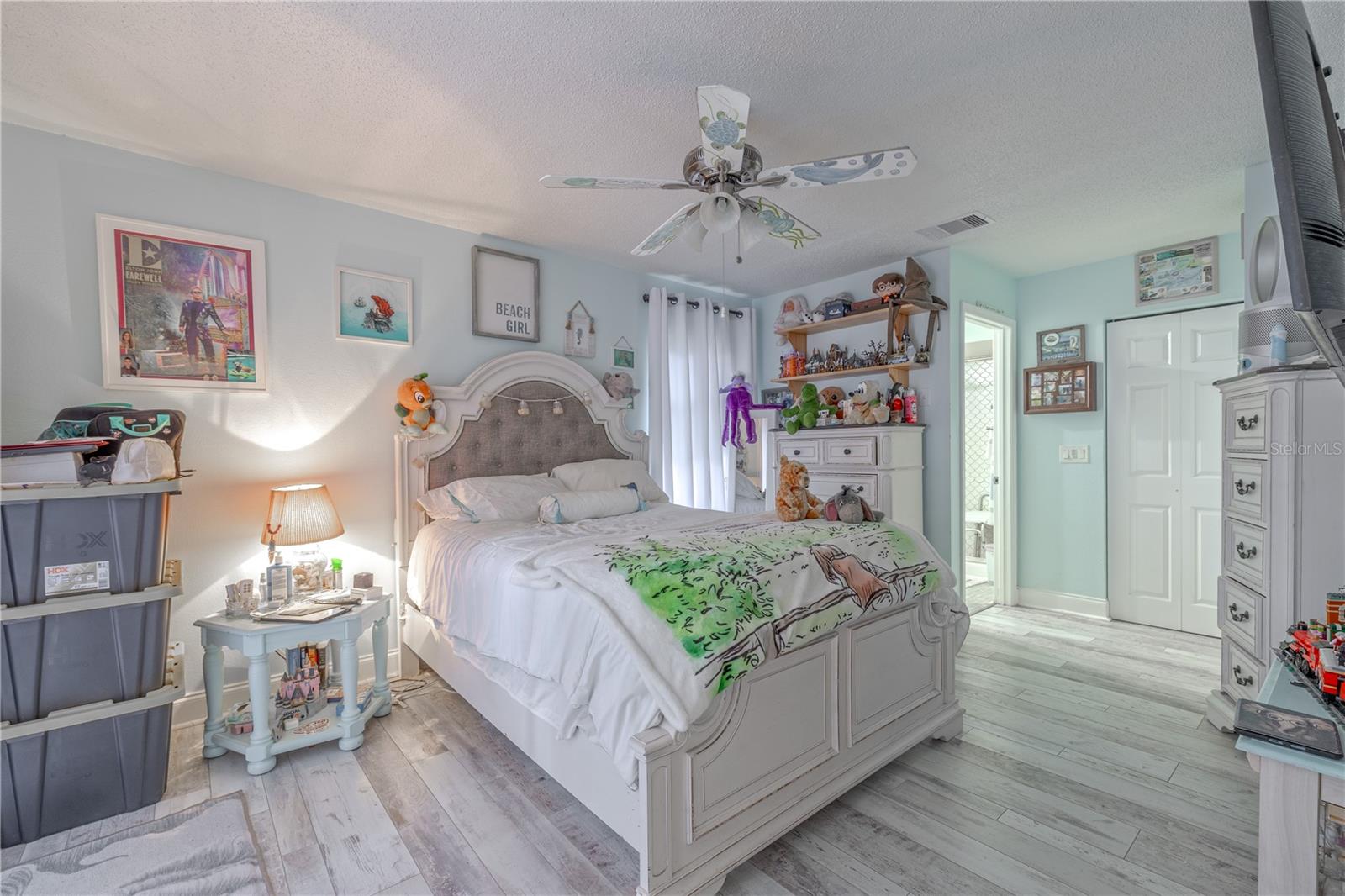 The room features durable and stylish wood-look vinyl flooring, a ceiling fan for comfort, and an en-suite bath. Double closets provide generous storage, while the layout comfortably accommodates a king-sized bed and additional furnishings.