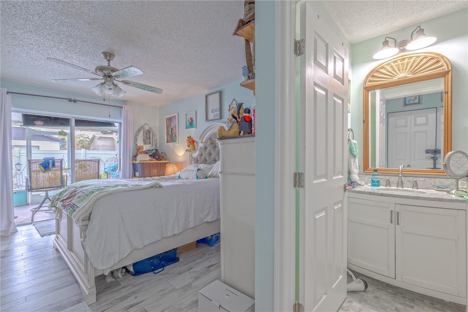 The spacious primary bedroom offers a peaceful retreat with ample natural light and direct access to the backyard oasis. A large sliding glass door opens to the patio and pool area, creating an easy indoor-outdoor flow.