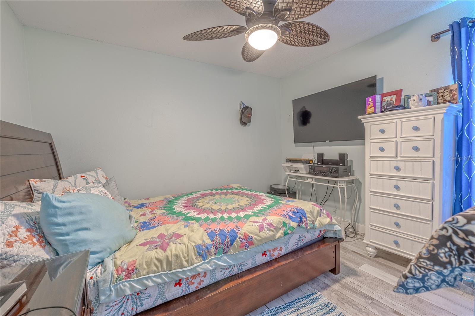 The second bedroom offers a cozy and comfortable space with wood-look vinyl flooring, a ceiling fan for added comfort, and a large window that brings in natural light. There's plenty of room for a full or queen-sized bed along with storage furniture, making it ideal for guests, family, or a home office.
