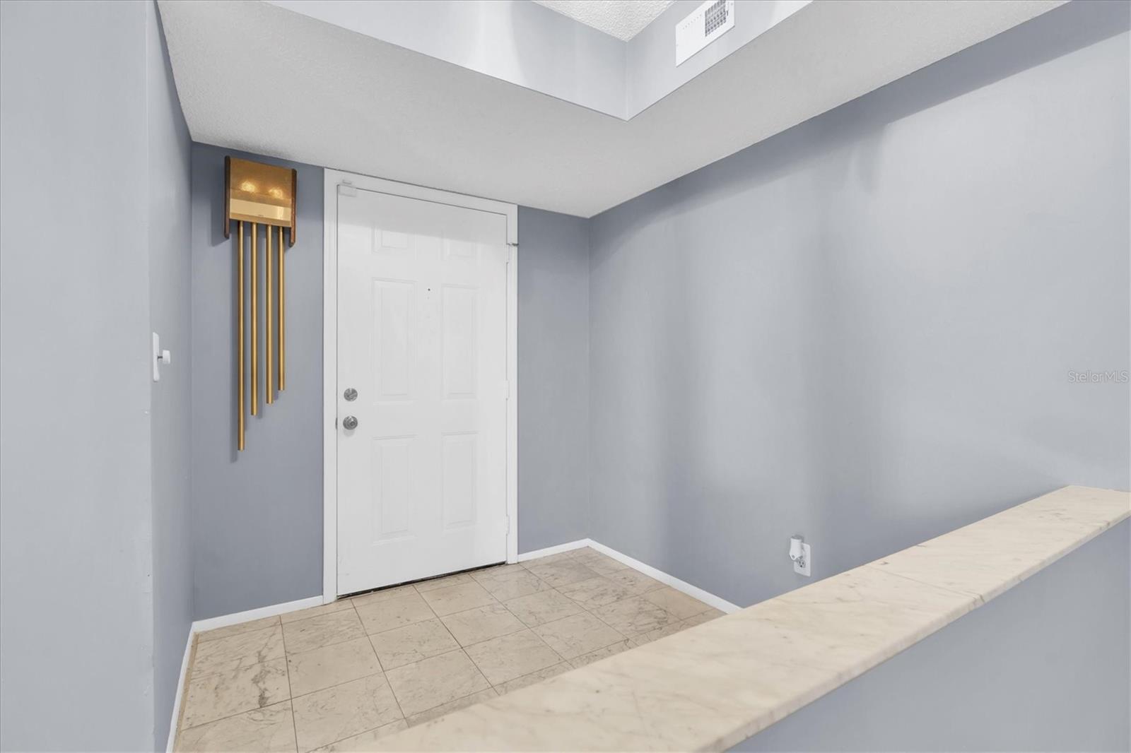 Interior entryway inside the unit with half wall looking into the dining room and open living area.