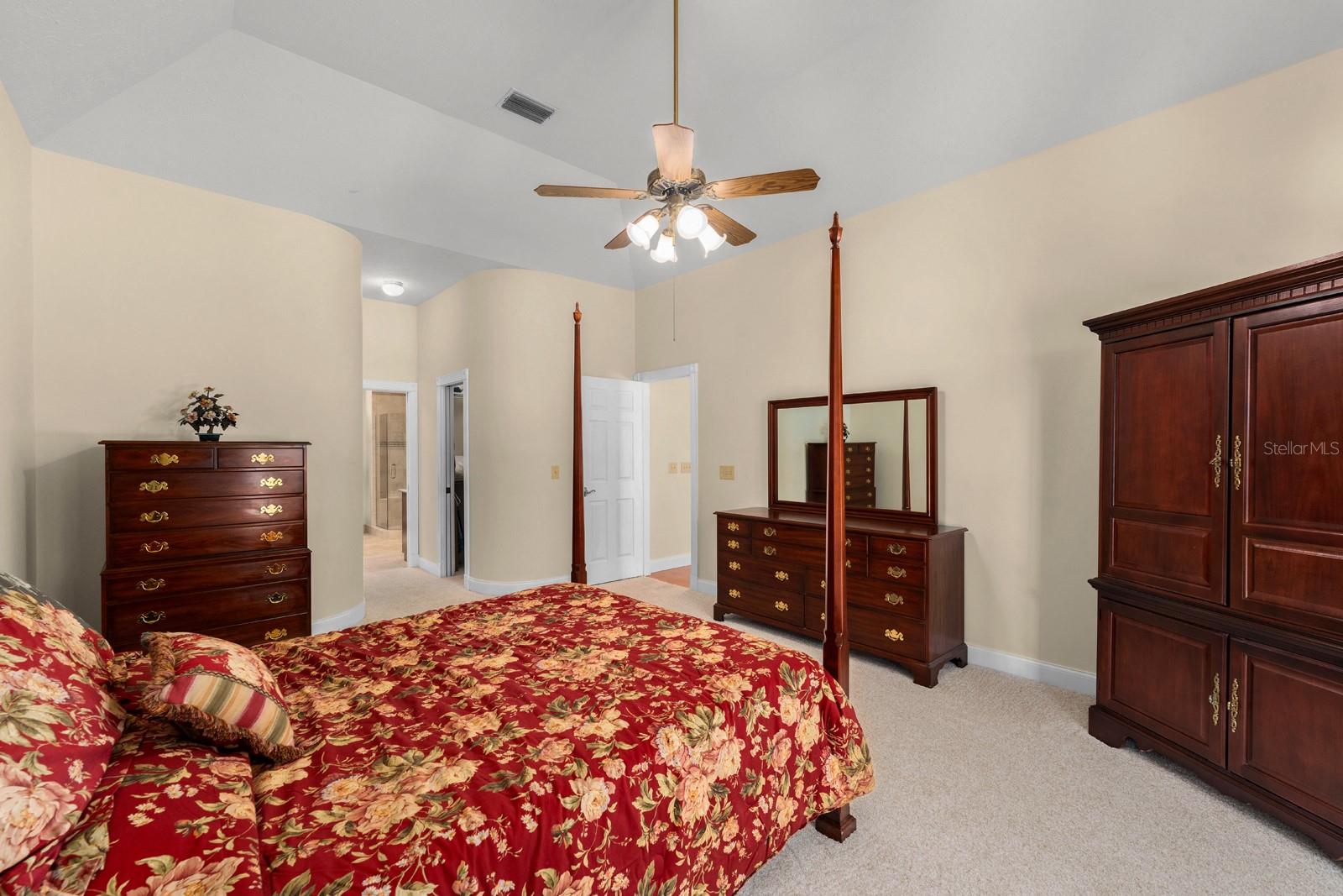 The oversized primary bedroom features two walk-in closets, a grand tray ceiling, brand new carpet (July 2025), a lighted ceiling fan, and a pocket slider to the lanai.