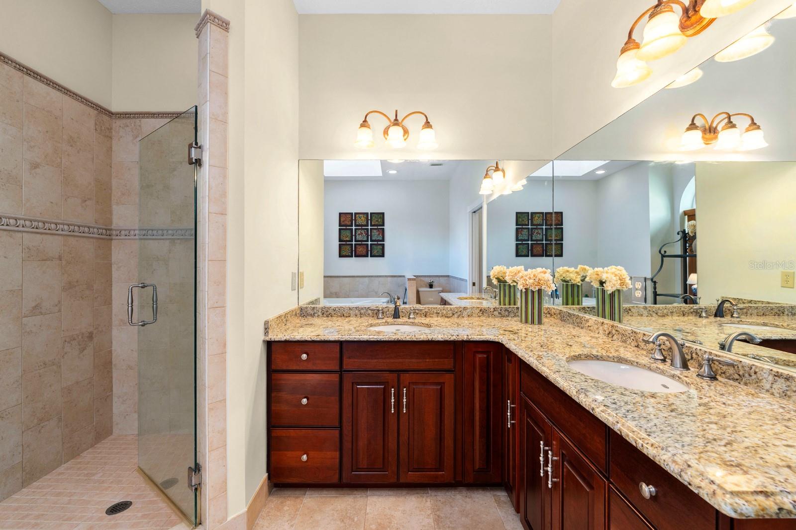 The updated primary ensuite features a walk-in shower, soaking tub, a large vanity with updated lighting, dual sinks, recessed lighting, and a beautiful window that could bring in lots of natural light.