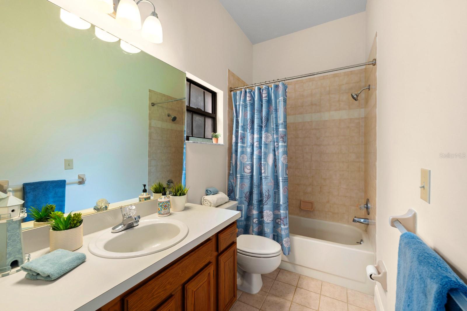The jack-n-jill bathroom has a tiled tub/shower combo, high ceiling, updated lighting, and ceramic tile flooring.