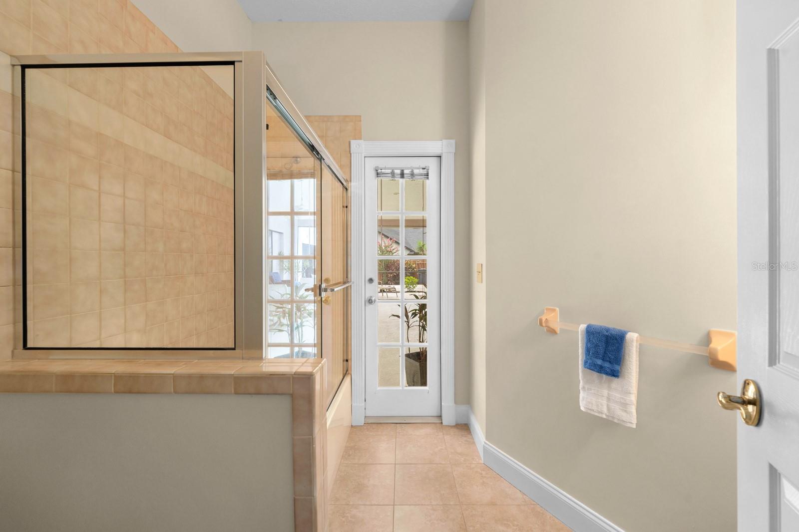 The full bathroom in the hallway (also the pool bathroom) features a tiled tub/shower combo, storage vanity sink, and a french door to the pool and lanai.