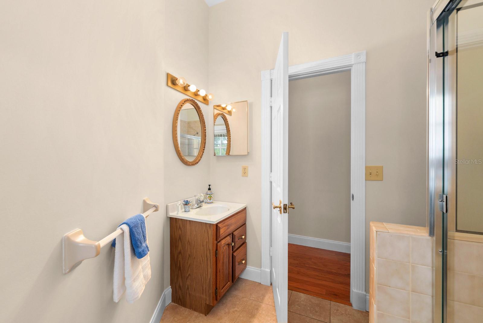 The full bathroom in the hallway (also the pool bathroom) features a tiled tub/shower combo, storage vanity sink, and a french door to the pool and lanai.