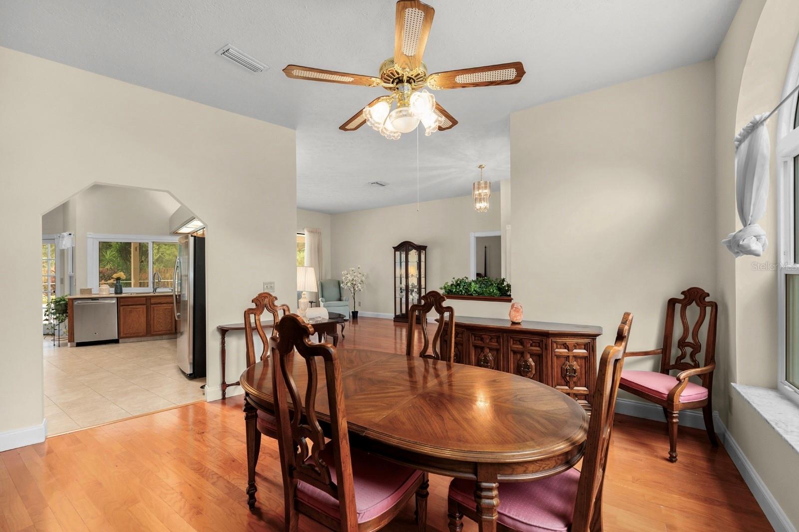 The dining room is very spacious, has the same wood flooring as the rest of the home, and features a lighted ceiling fan.