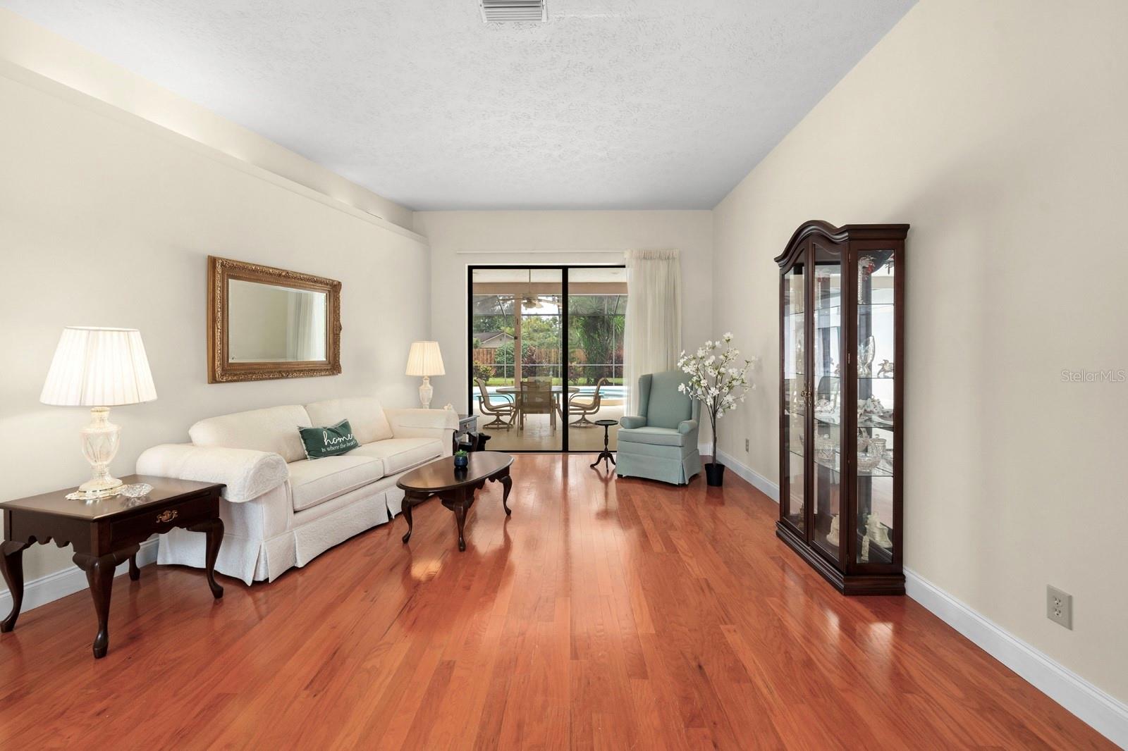 The living room is straight ahead, inside the front door and features the same hardwood flooring as the rest of the home, as well as a pocket slider to the lanai and pool.