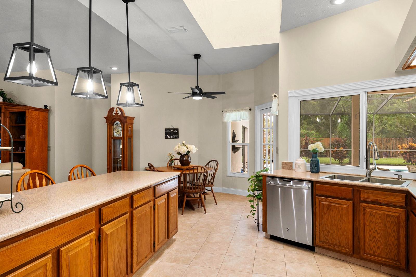 This classically beautiful kitchen features top-tier granite countertops, newer stainless appliances, solid wood cabinets, a newer stainless sink, a skylight above, new recessed lighting was added, ceramic tile flooring, and was opened up to the Great Room with updated pendant lights added.