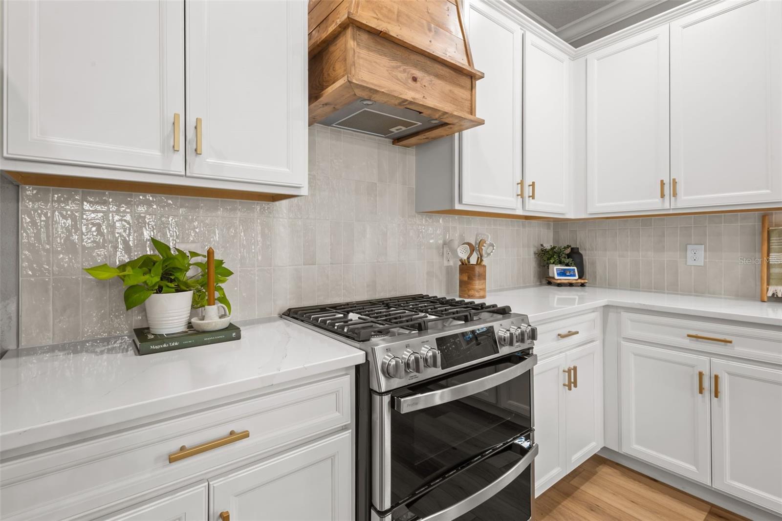 Custom range hood, backspash, stainless steel appliances, and gas range