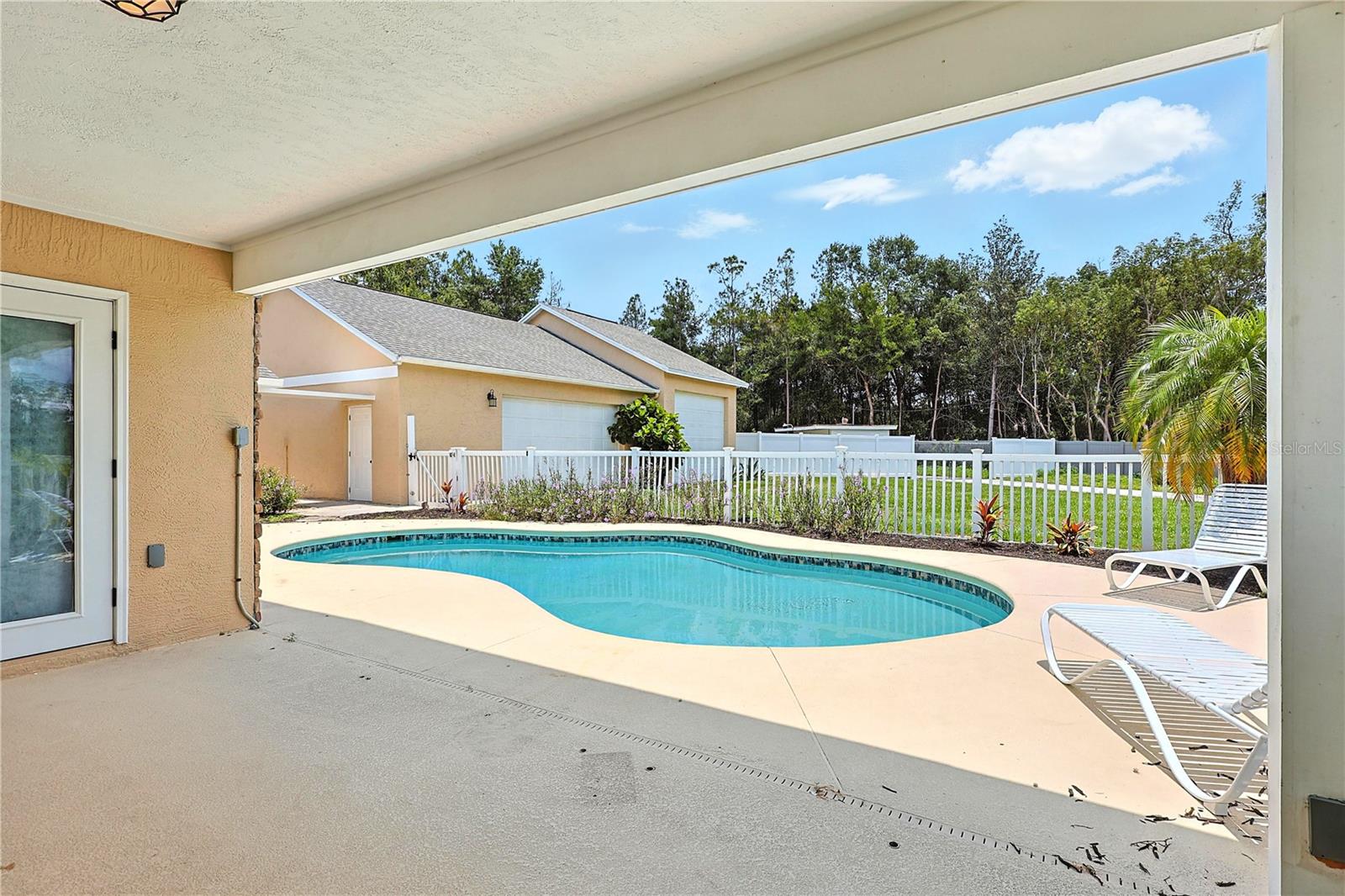 Pool with view of backyard and detached garage-covered patio area