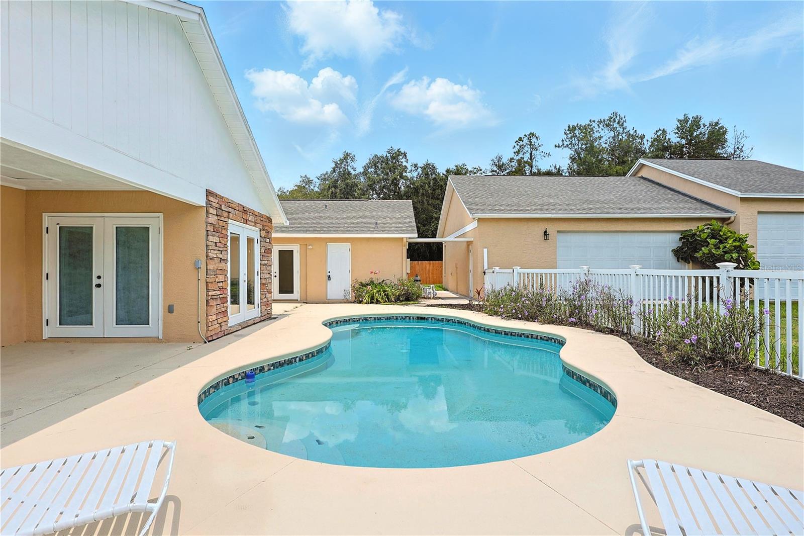 Pool with view of standalone garage and doors leading to master bedroom