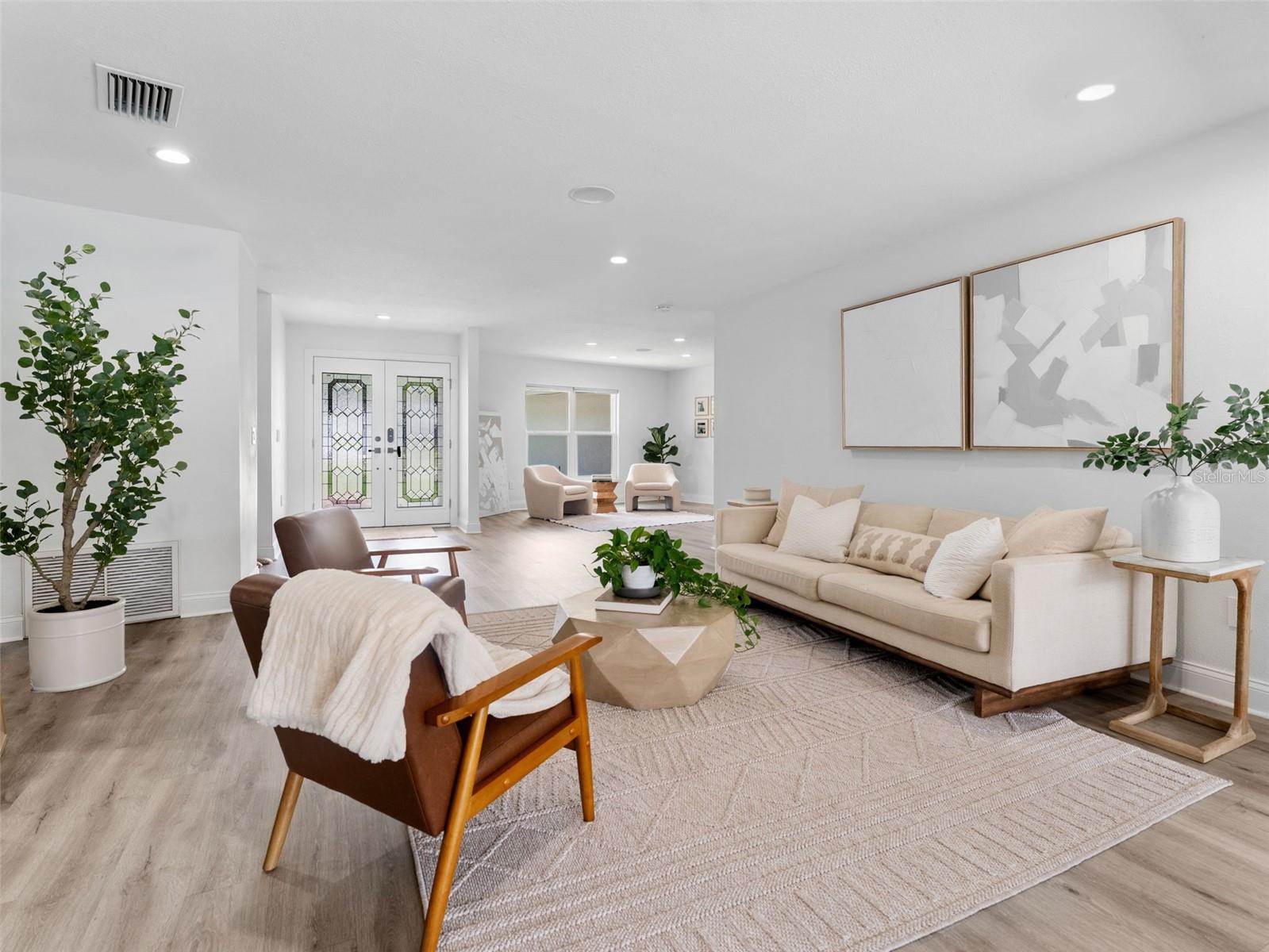 Beautiful front doors, gorgeous flooring, and a neutral color palette create a harmonious space to talk and relax.