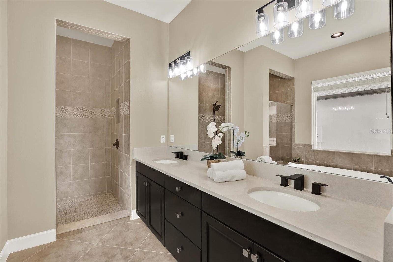 Primary bathroom features dual sinks, quartz counters and beautiful walk-in shower
