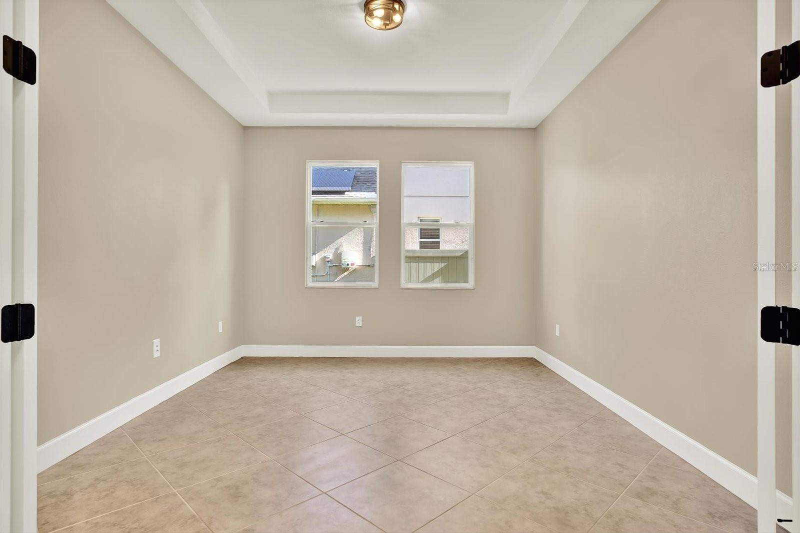 Office features tray ceiling and glassed-in French doors
