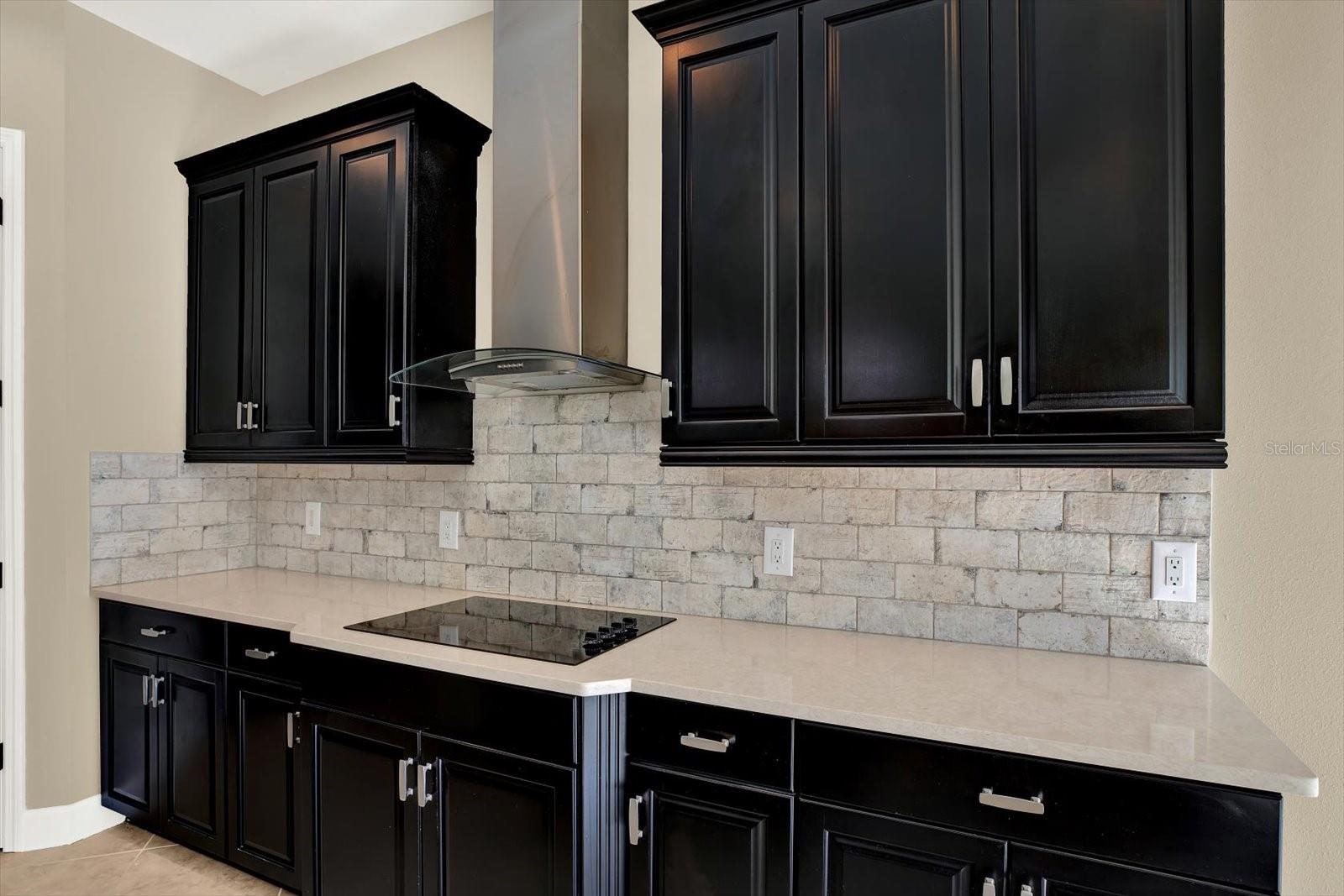 Subway tile backsplash and stainless range hood provide a touch of elegance