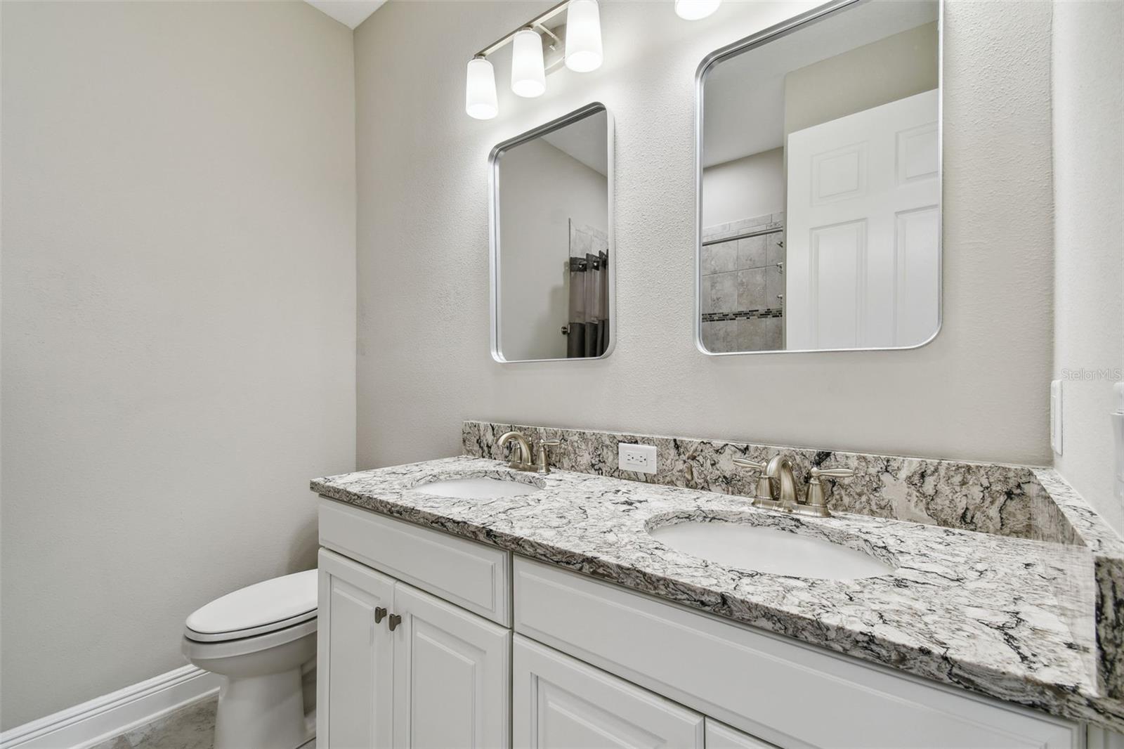The shared bathroom has plenty of cabinet space, dual sinks, and a bath