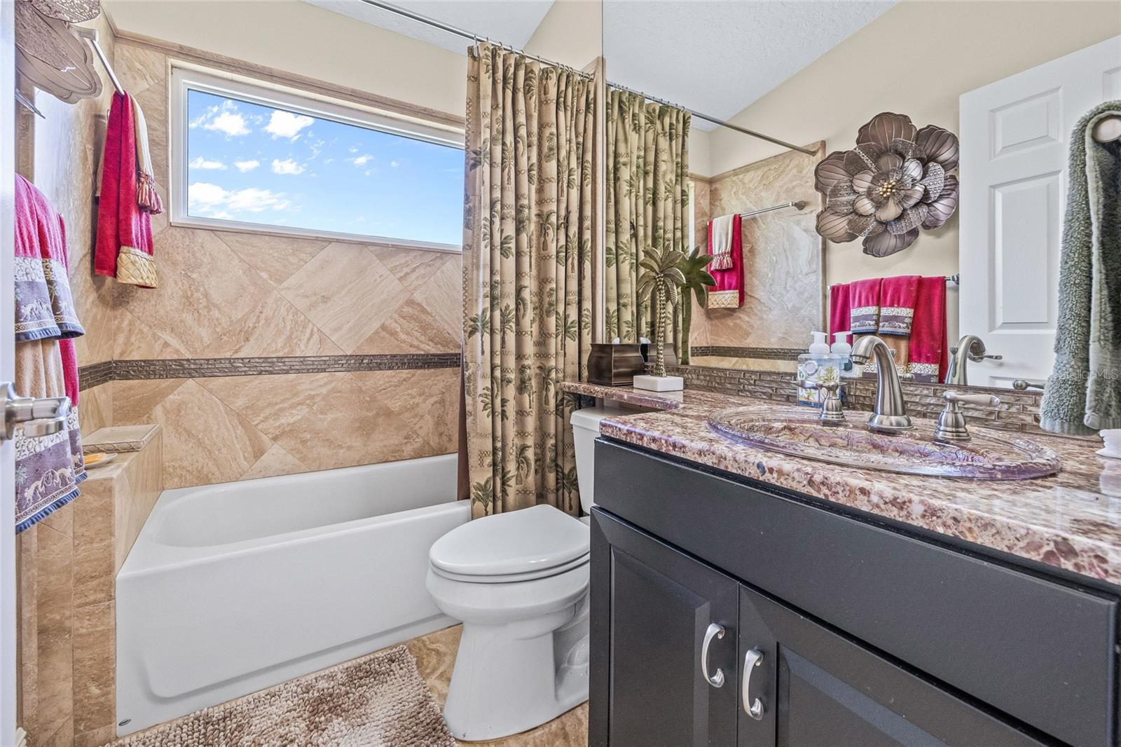 Guest bath includes a custom stone vanity and a bathtub.