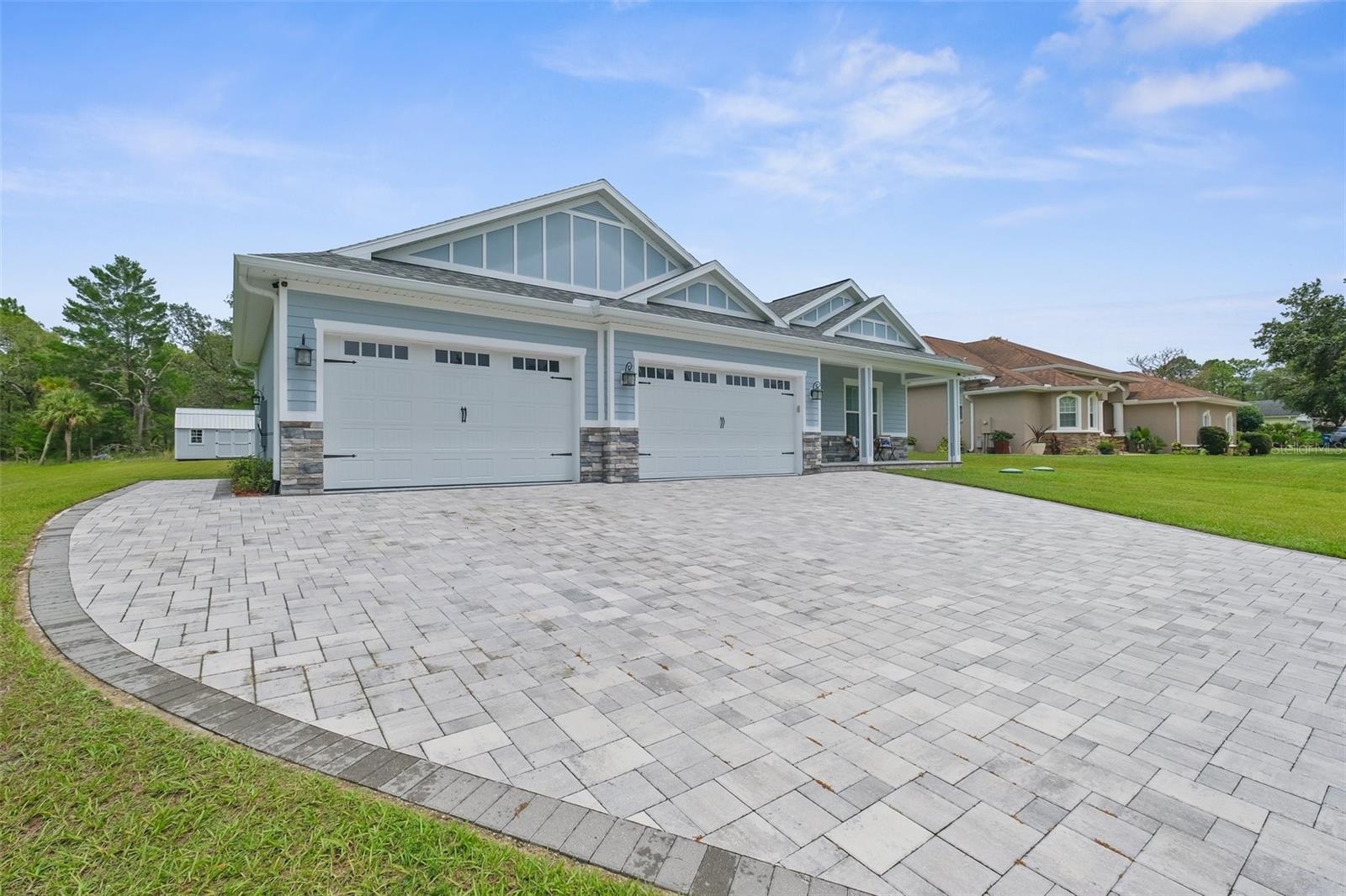 4-car garage with wide paver driveway.