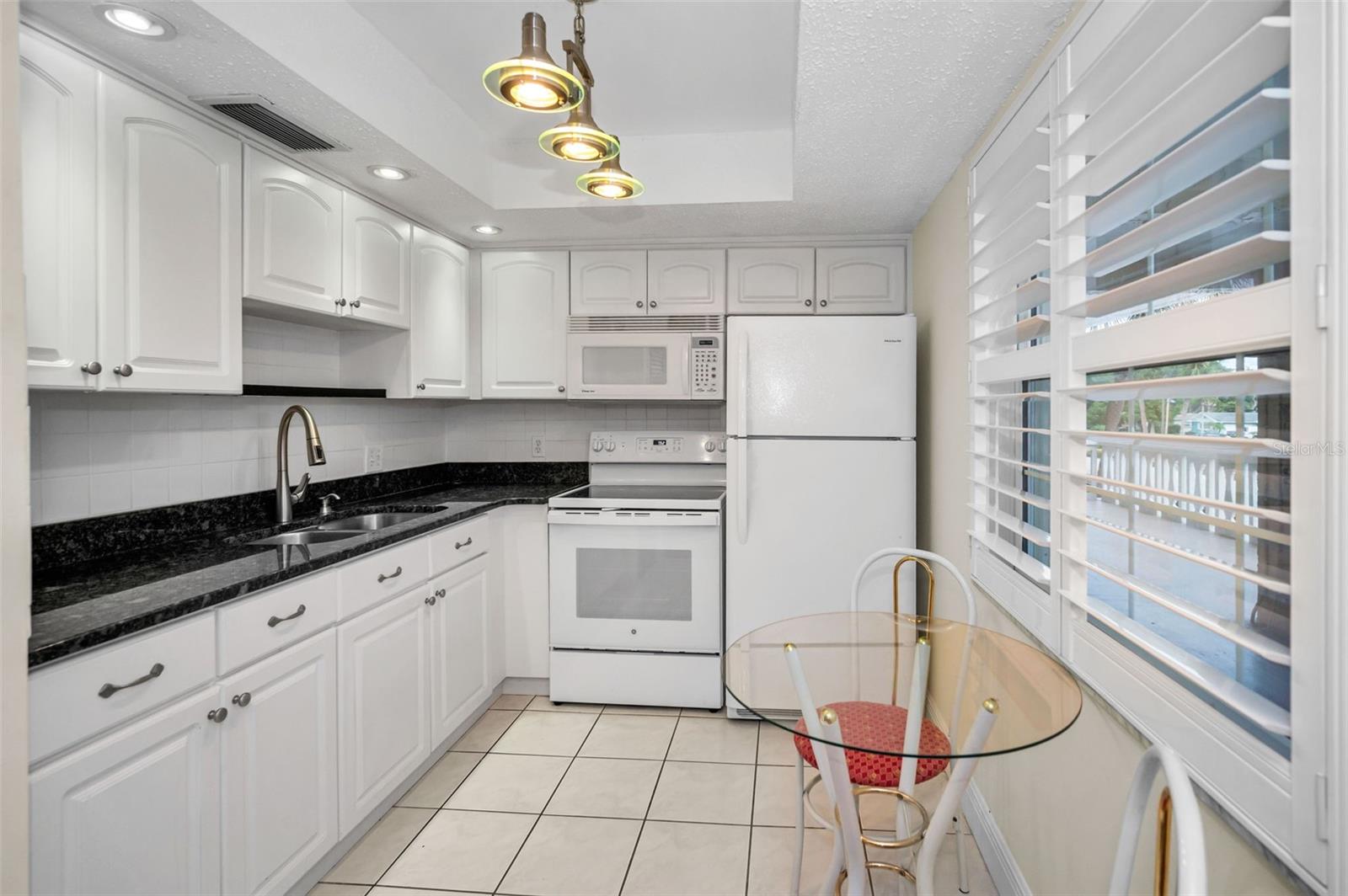 REMODELED KITCHEN WITH GRANITE COUNTERTOPS, NEWER FAUCET, NEWER CABINETS, NEWER LIGHTING, NEWER APPLIANCES AND PLANTATION SHUTTERS.