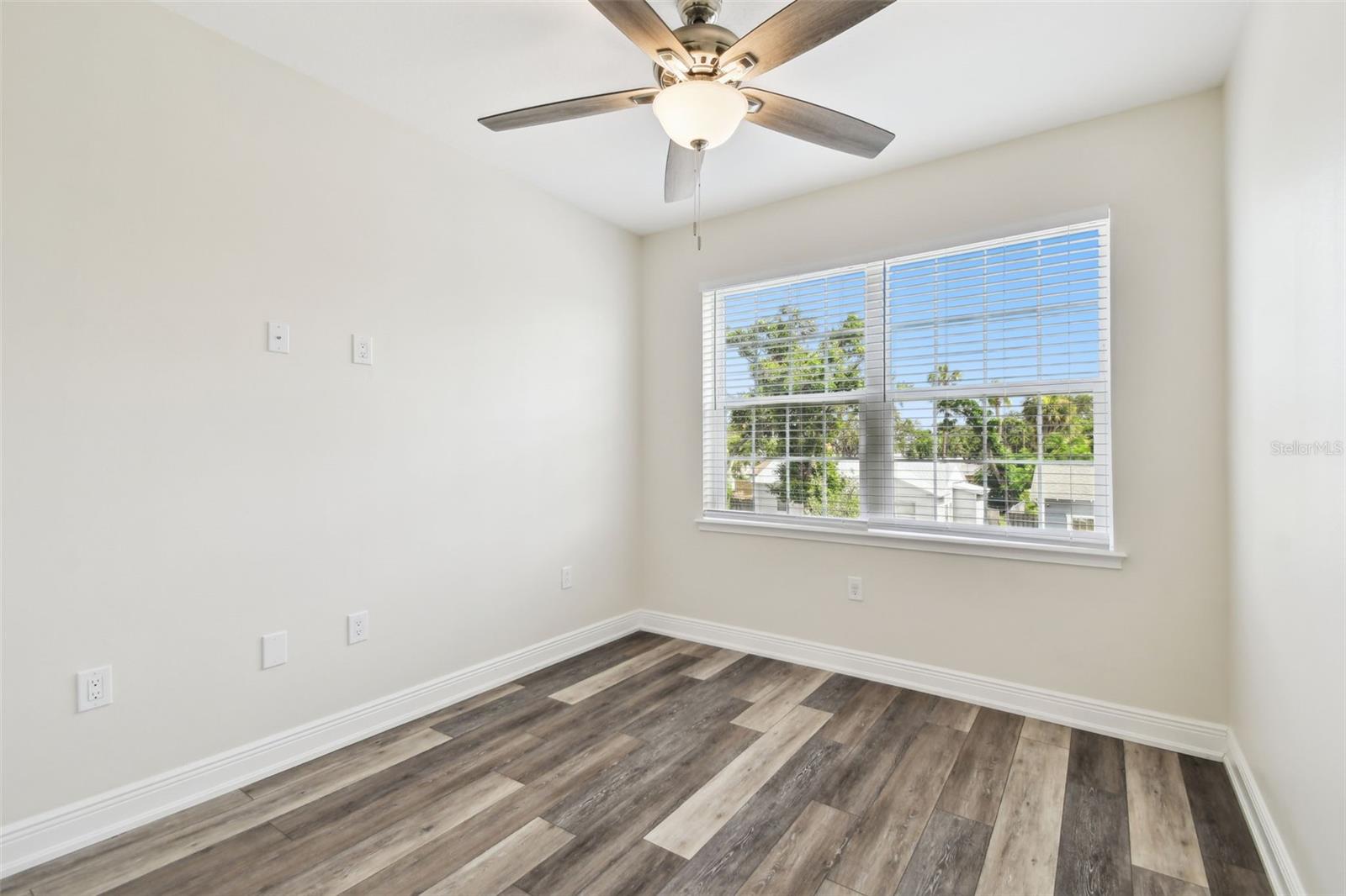 Bedroom 2 - fresh paint, ceiling fan, blinds and large window overlooking front of home.