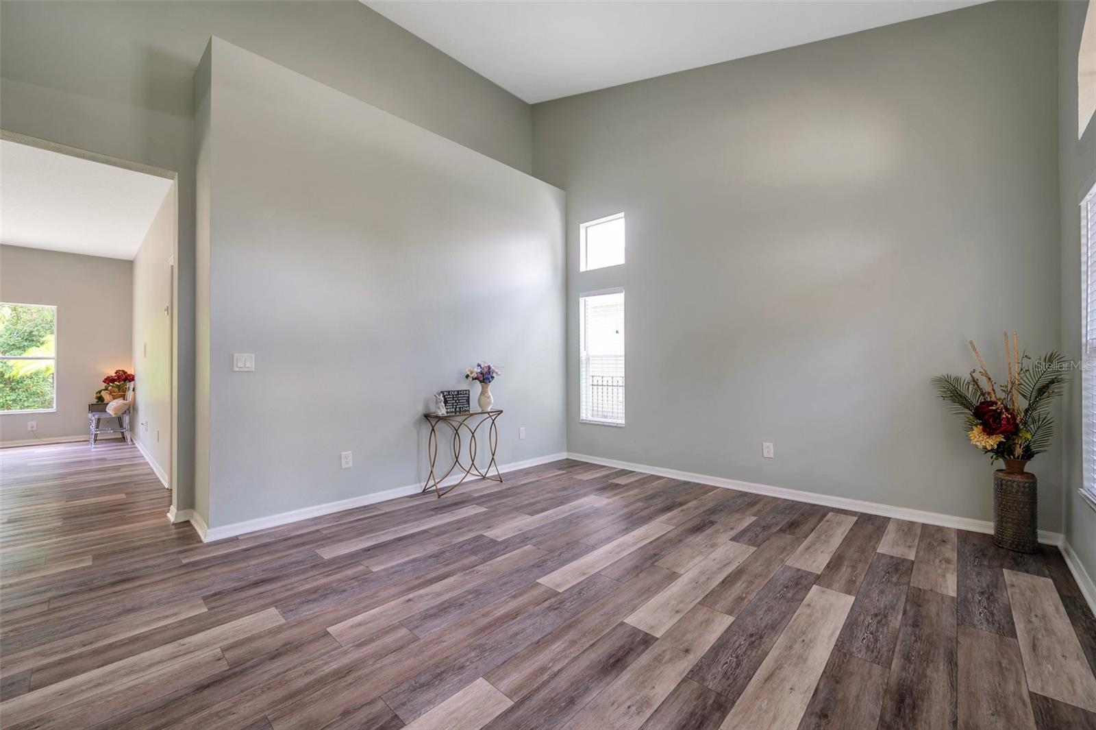 Formal living room has soaring ceilings & plant shelf.