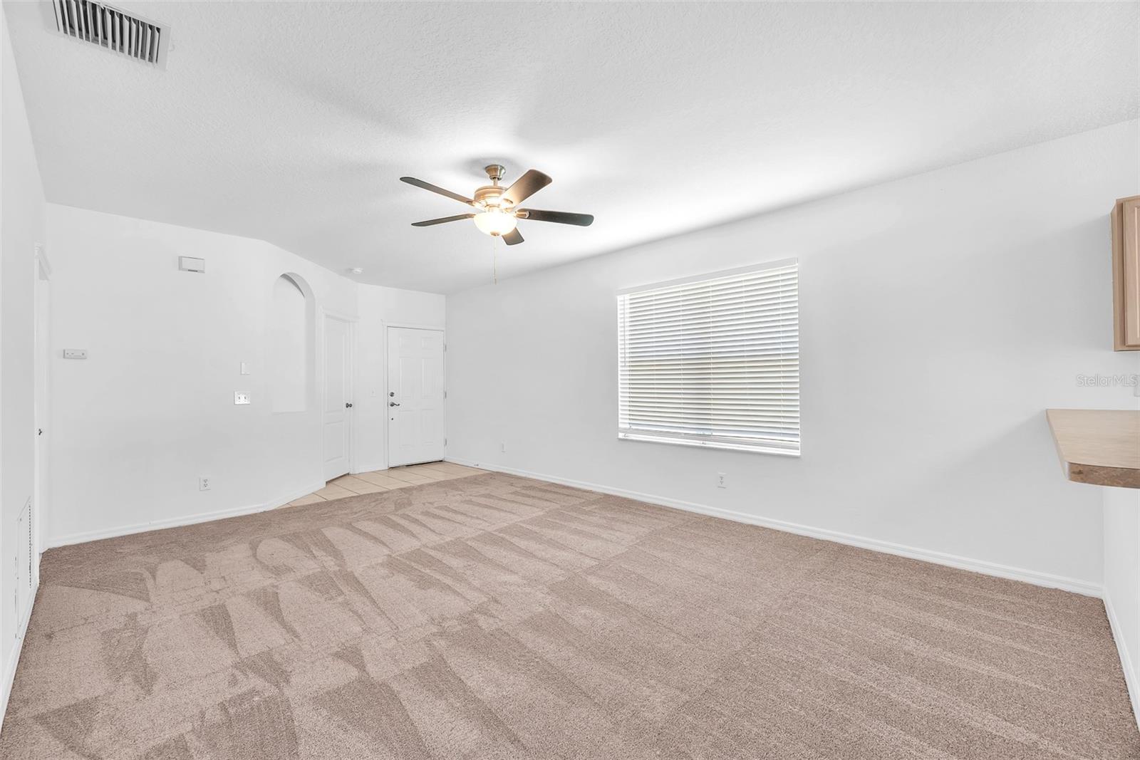 Great room plan with breakfast bar from the kitchen showing on the right. Notice the fresh paint and carpet throughout.