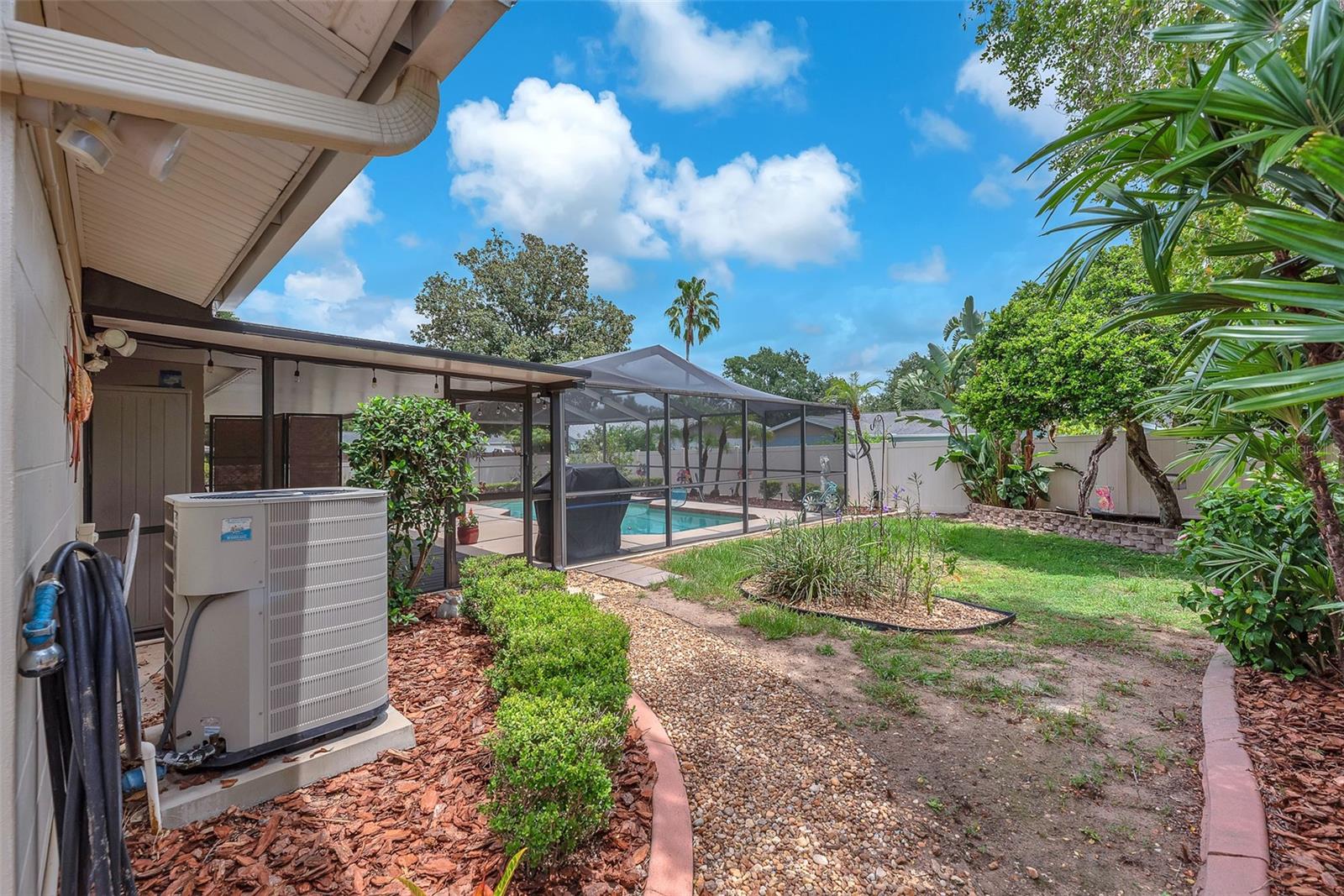 View of side yard and lush florida landscaping with curbing.